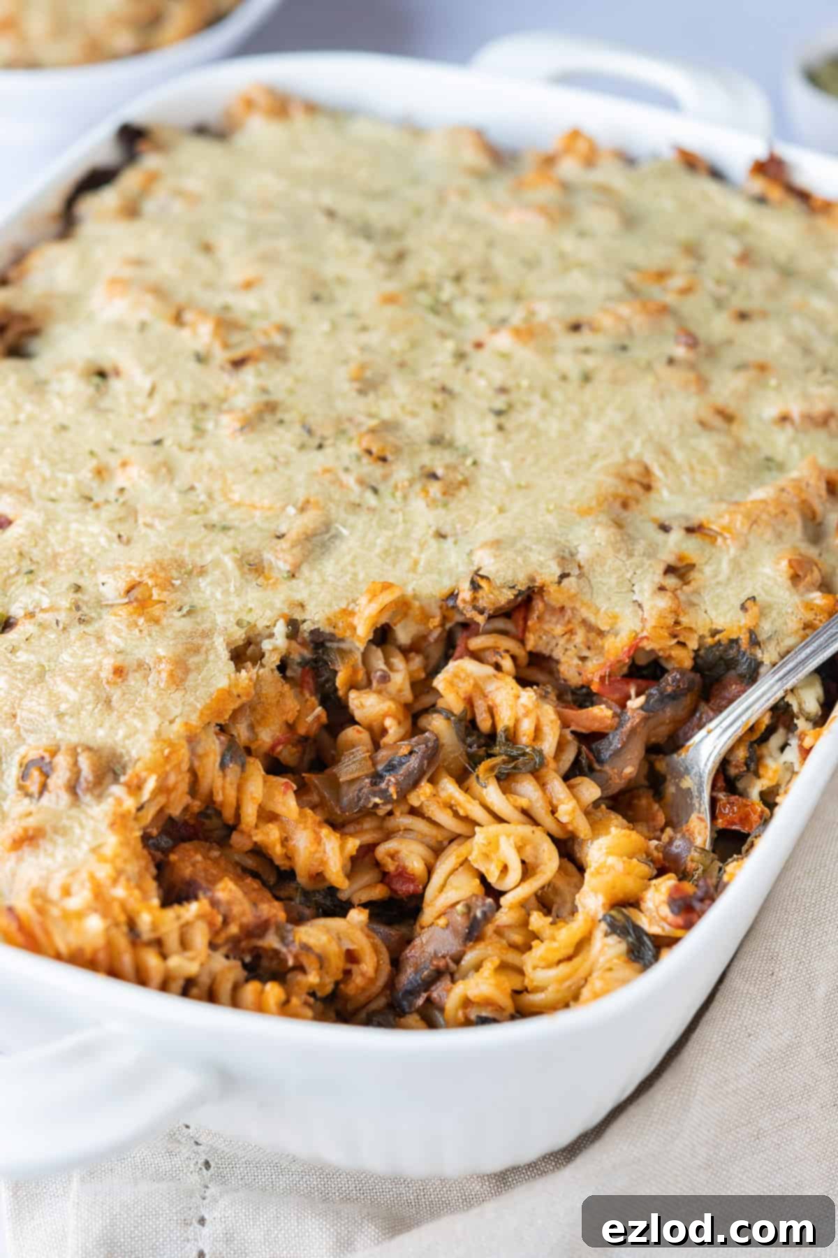 Golden & Bubbly Vegan Pasta Bake A close-up view of the baked vegan pasta with a creamy golden topping, showing visible pasta and sauce underneath.