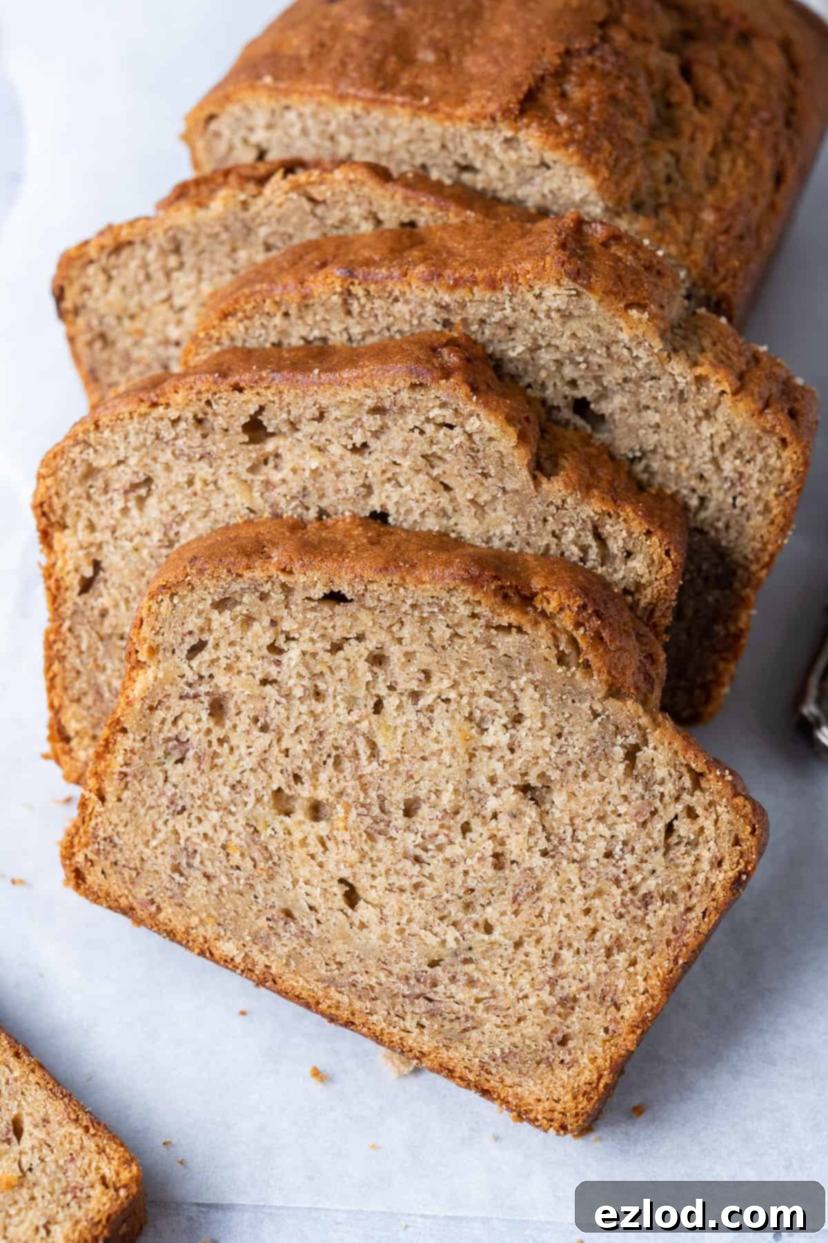 Close-Up of a Delicious Slice of Easy Vegan Banana Bread A close-up shot of a single, perfectly cut slice of easy vegan banana bread, showcasing its beautiful crumb and golden-brown exterior.