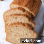 Simply Delicious Vegan Banana Bread 4 Sliced easy vegan banana bread on a sheet of white baking parchment on a light grey background.