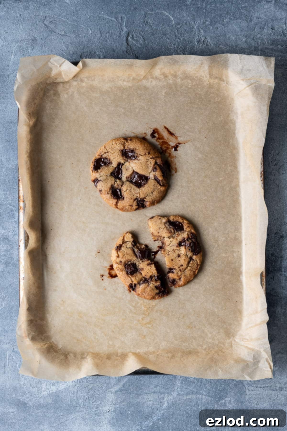Freshly Baked Vegan Chocolate Chip Cookies for One Two freshly baked small batch vegan chocolate chip cookies cooling on a baking tray, showcasing their perfectly golden and chewy appearance.