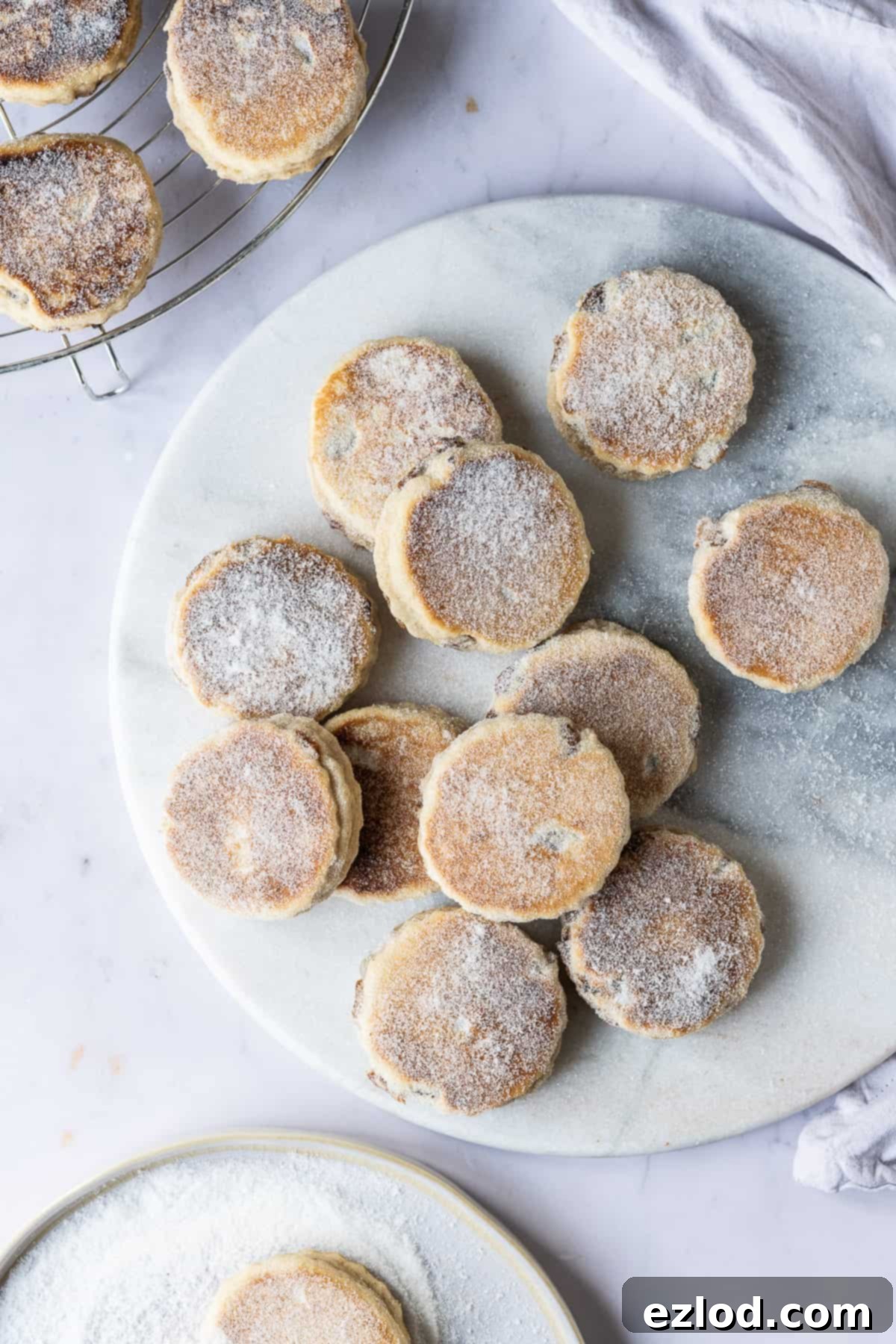 Homemade Dairy-Free Welsh Cakes - Perfect Vegan Snack Vegan Welsh cakes cooling on a wire rack next to a marble board.