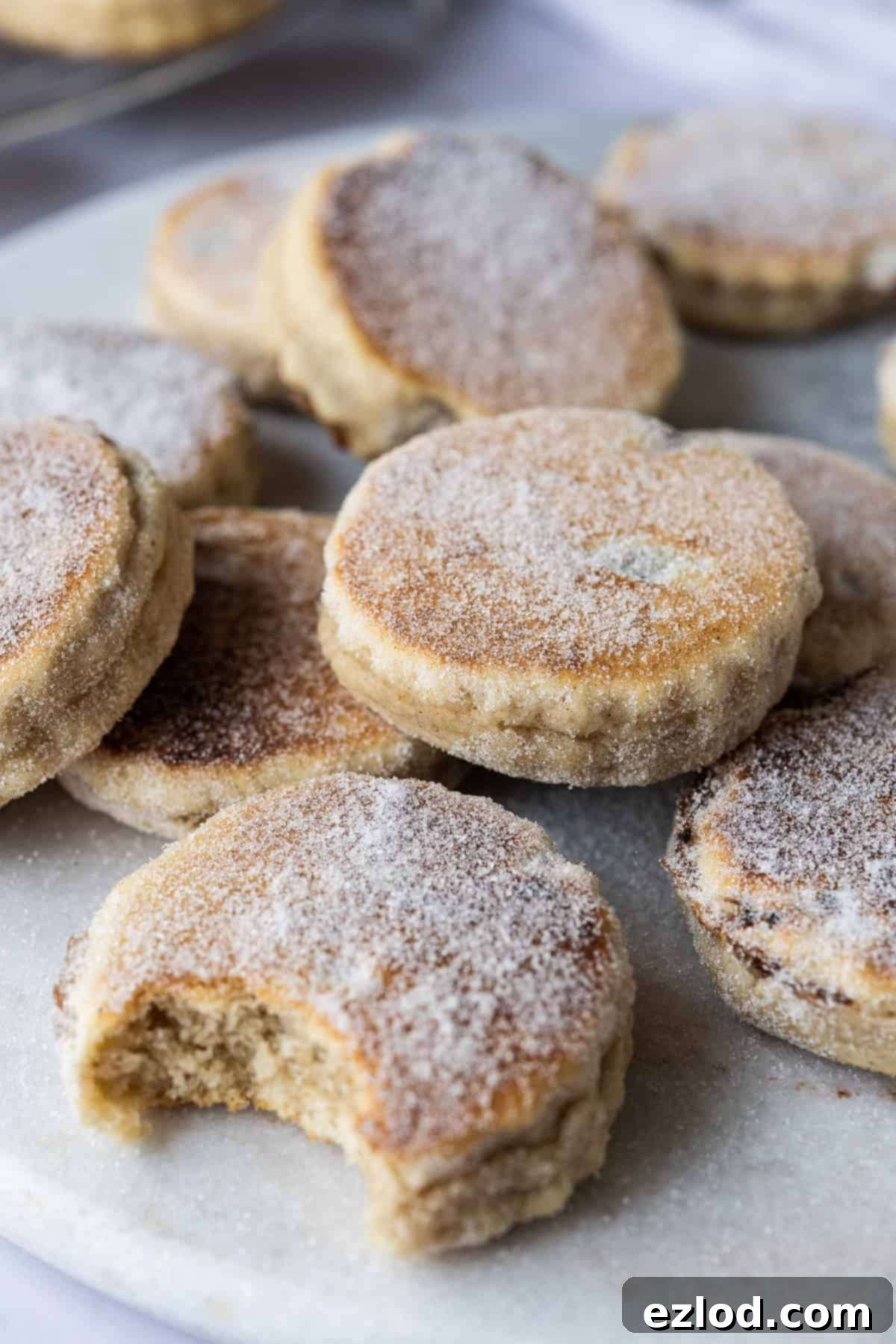 Enjoying a Freshly Baked Vegan Welsh Cake A stack of vegan Welsh cakes on a marble board, with one cake having a bite taken out of it.