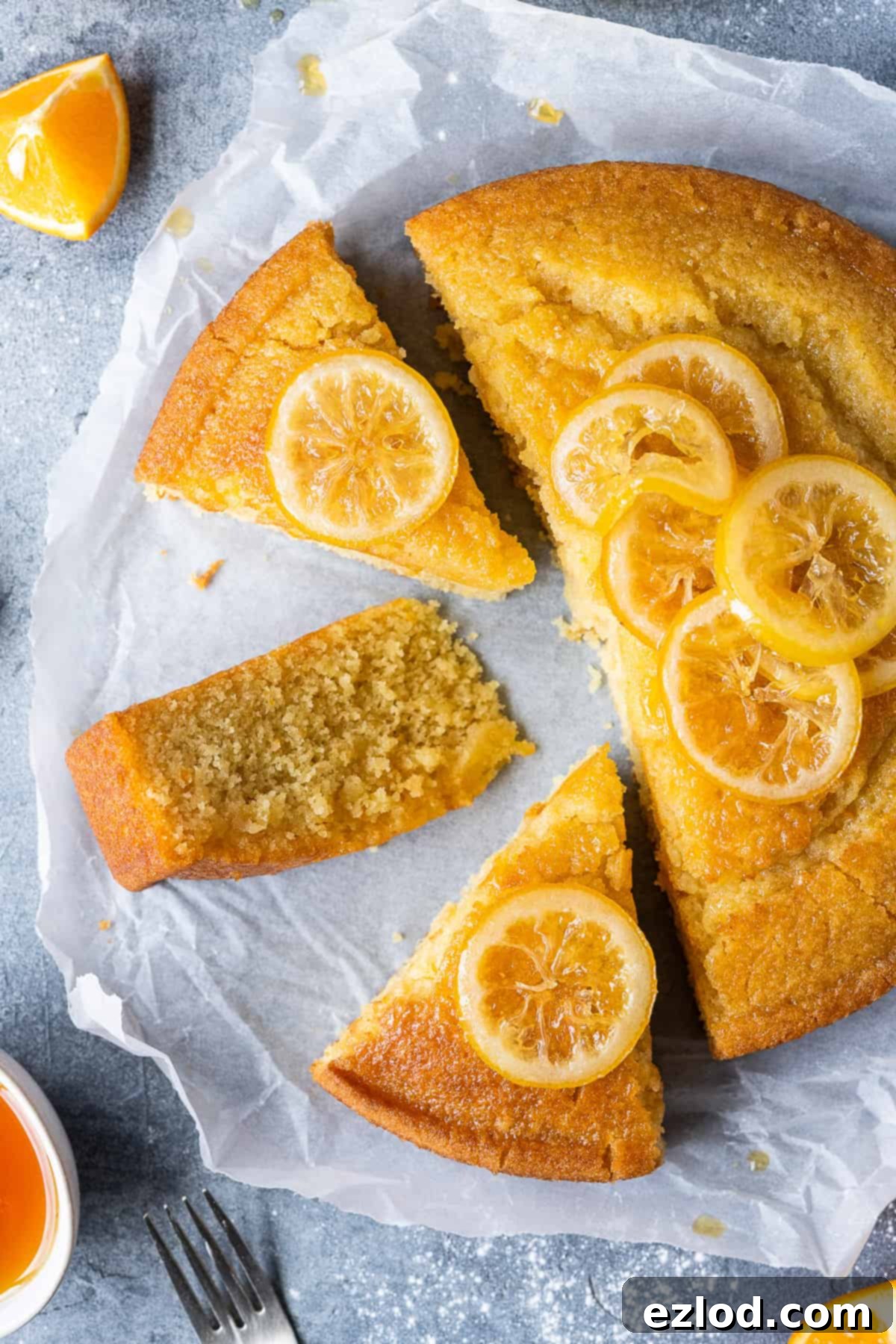 Vegan Semolina Cake Slices with Candied Lemon Multiple slices of vegan semolina cake topped with candied lemon slices, arranged neatly on a sheet of white baking parchment