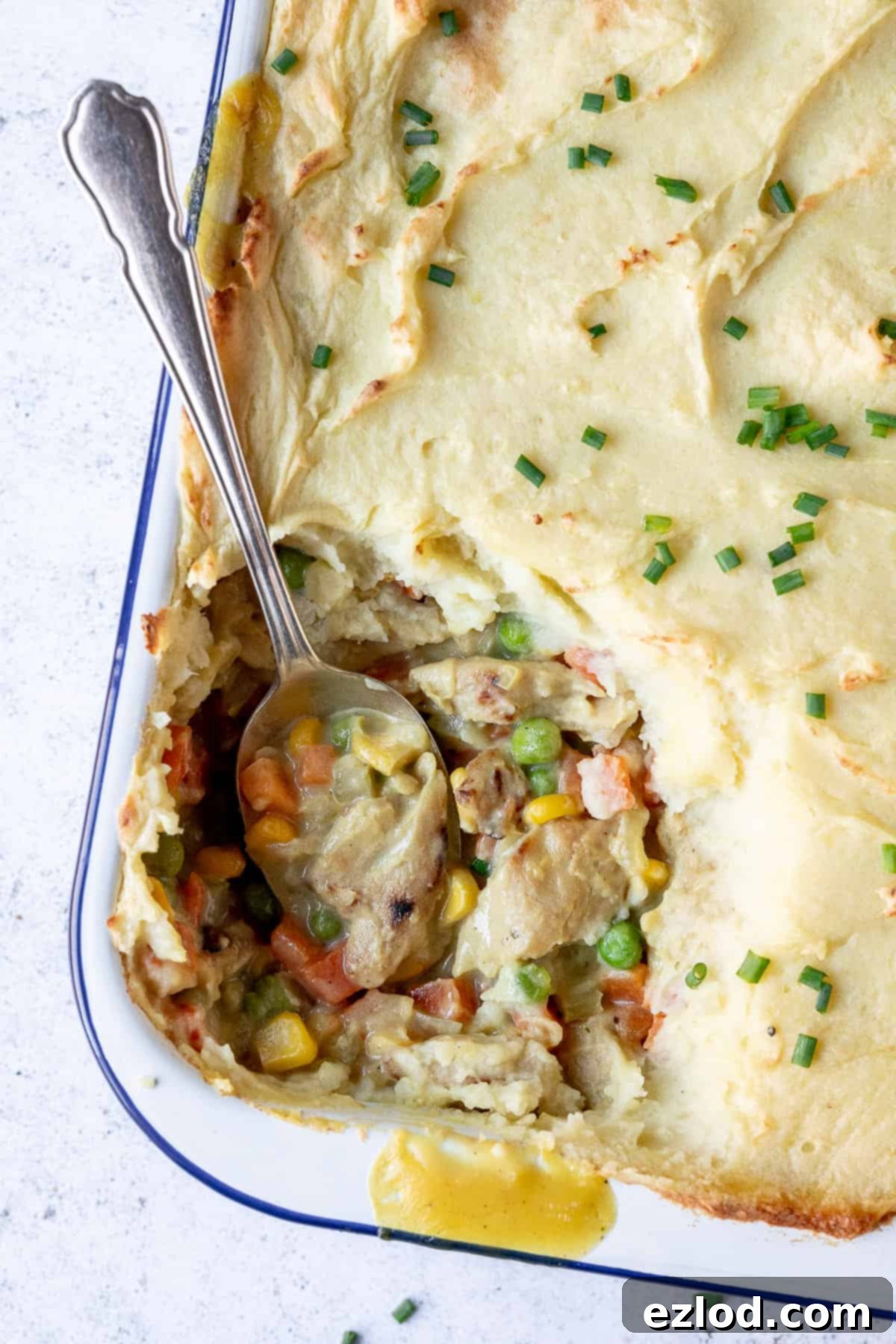 A delicious portion of vegan chicken potato pie scooped out, ready to enjoy. Hearty and wholesome vegan comfort food. A serving of vegan chicken potato pie with a spoonful removed, revealing the rich filling and soft potato.