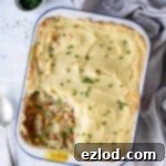Delicious Plant-Based Chick'n and Potato Pie 2 Vegan chicken potato pie in an enamel dish on a white background with a grey cloth and chopped chives.