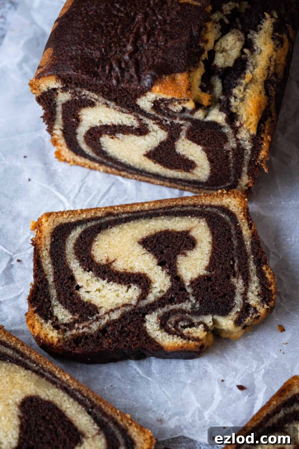 Vegan marble cake - this vegan chocolate and vanilla pound cake is moist, soft and very moreish! It makes a great snack or indulgent breakfast and just look at those swirls! Eggless and dairy-free. #vegancake #veganbaking #loafcake #eggless A close-up view of a slice of vegan marble cake, showcasing the intricate chocolate and vanilla swirls and its perfectly moist texture.