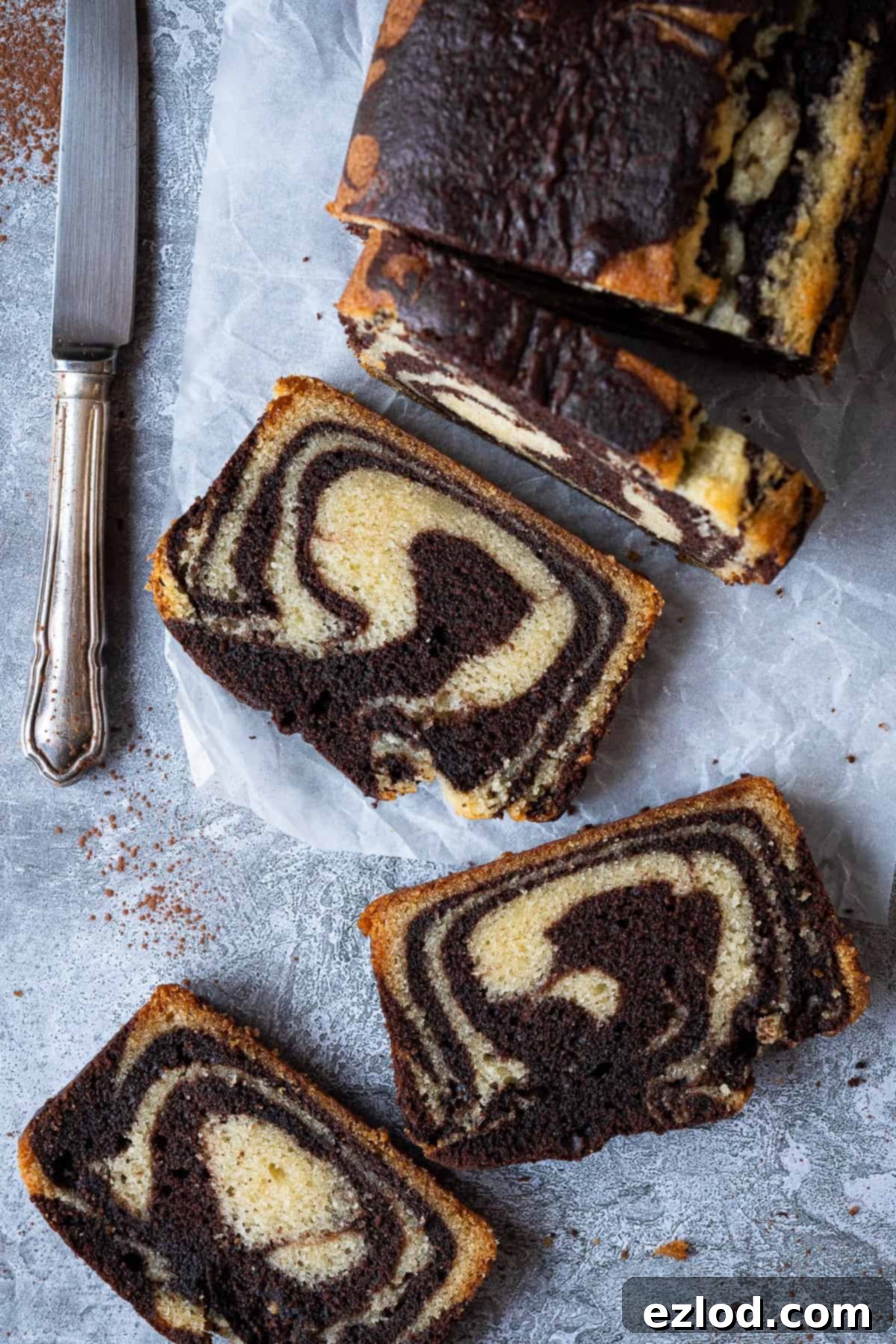 Vegan marble cake - this vegan chocolate and vanilla pound cake is moist, soft and very moreish! It makes a great snack or indulgent breakfast and just look at those swirls! Eggless and dairy-free. #vegancake #veganbaking #loafcake #eggless A perfectly baked and sliced loaf of vegan marble cake, displaying a beautiful cross-section of swirls, rests on a neutral grey background.