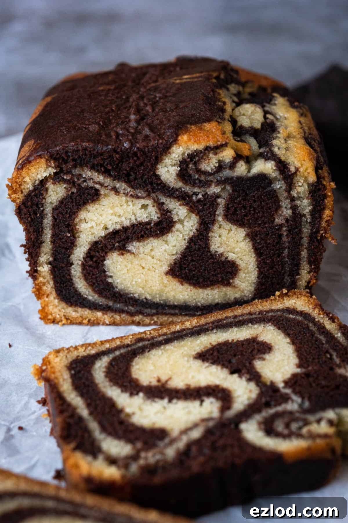 Vegan marble cake - this vegan chocolate and vanilla pound cake is moist, soft and very moreish! It makes a great snack or indulgent breakfast and just look at those swirls! Eggless and dairy-free. #vegancake #veganbaking #loafcake #eggless A close-up of the end of a loaf of sliced vegan marble cake, showing the perfect swirls within each slice.