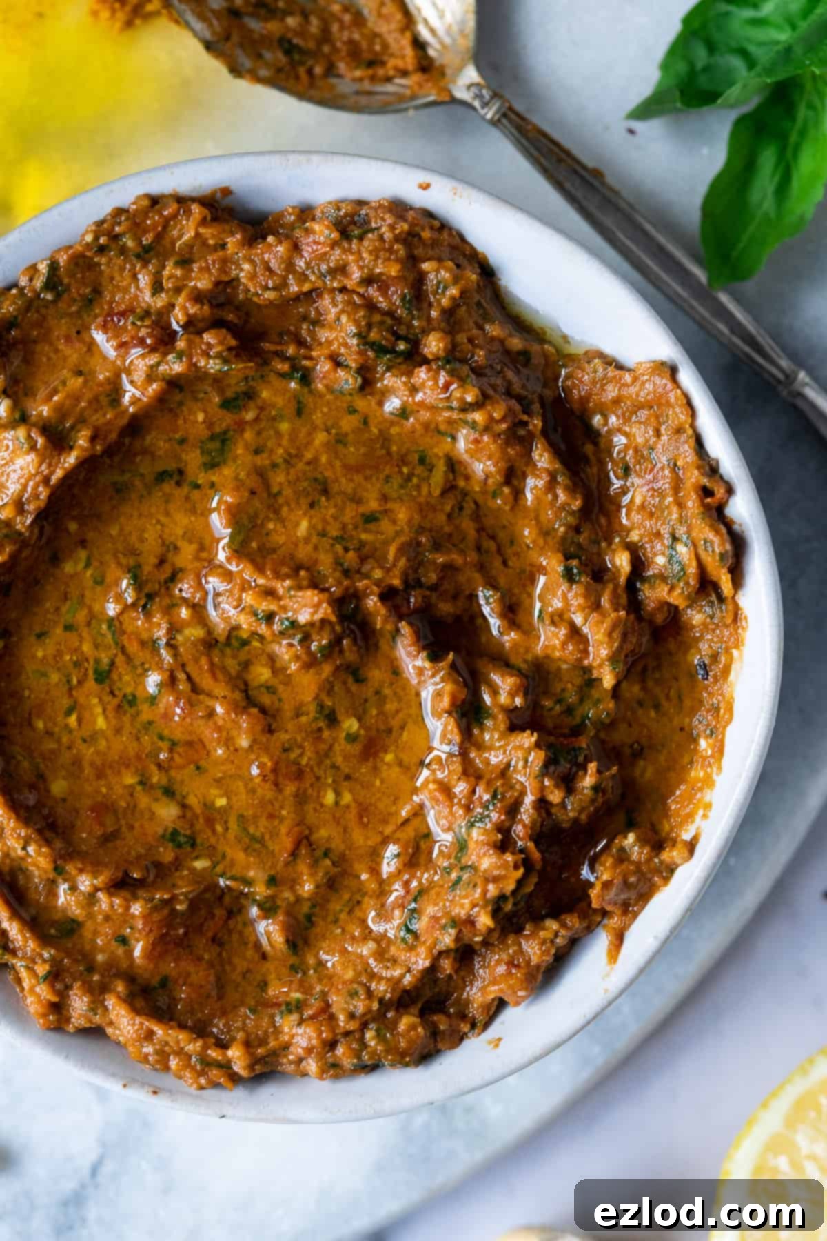 Homemade Vegan Sun-Dried Tomato Pesto - Dairy-Free Pesto Rosso in a White Bowl. Delicious and Easy Plant-Based Recipe for Pasta and Dips. #veganpesto #dairyfree #plantbased A close-up shot of rich, red vegan sun-dried tomato pesto perfectly scooped into a clean white bowl, highlighting its smooth yet textured consistency and inviting color.