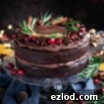 Mulled Wine-Infused Vegan Chocolate Cake 5 Vegan mulled wine chocolate cake topped with cranberries, rosemary, star anise and cinnamon sticks on a glass cake stand on a wooden table.