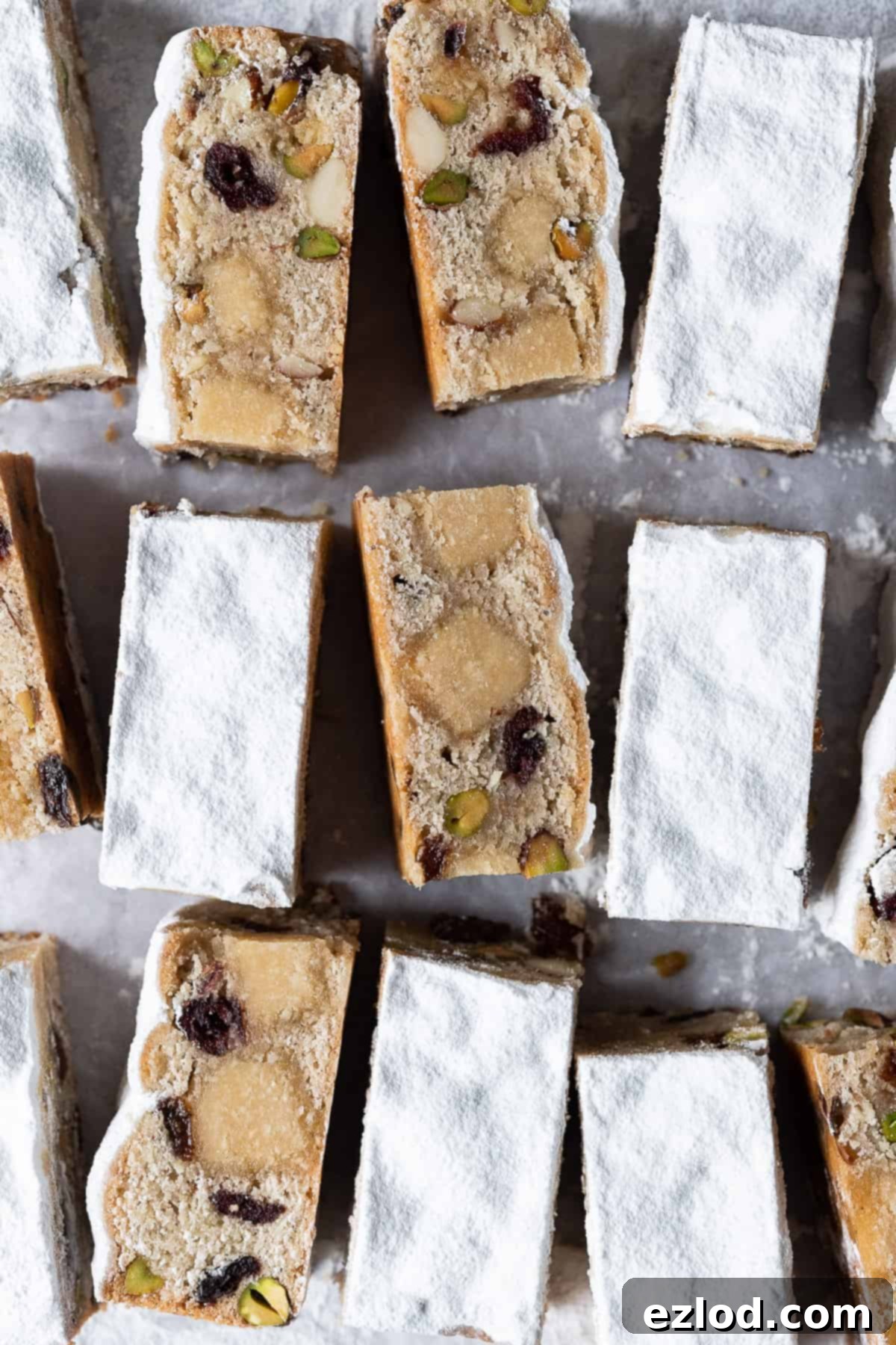 Vegan Stollen Bars - Quick & Easy No-Yeast Christmas Recipe with Marzipan, Fruit, and Spices. Top down shot of easy vegan stollen bars, some on their side, dusted with powdered sugar.