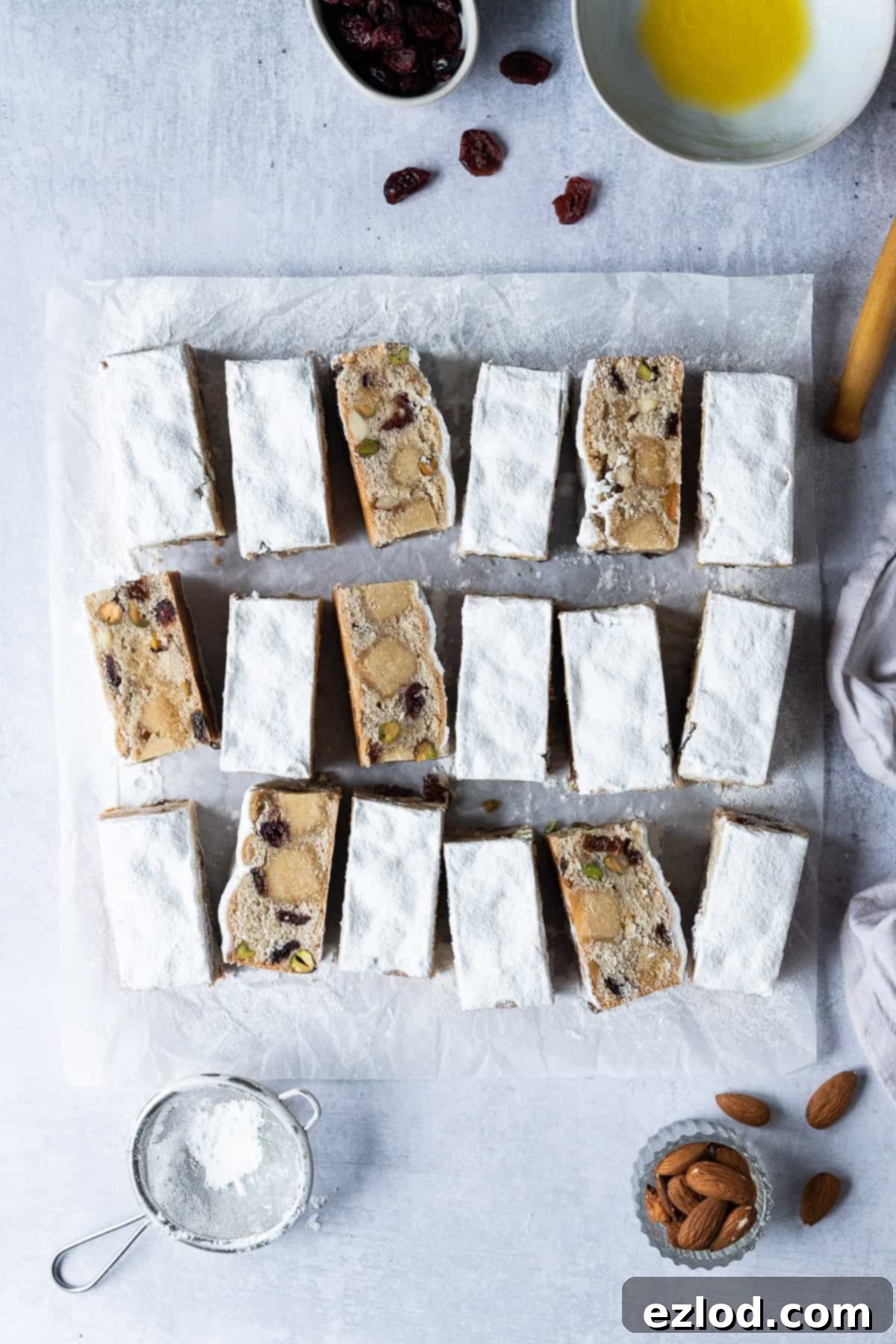 Festive Vegan Stollen Bars: Perfect for Holiday Snacking. Arrangement of vegan stollen bars on a grey background with baking ingredients.