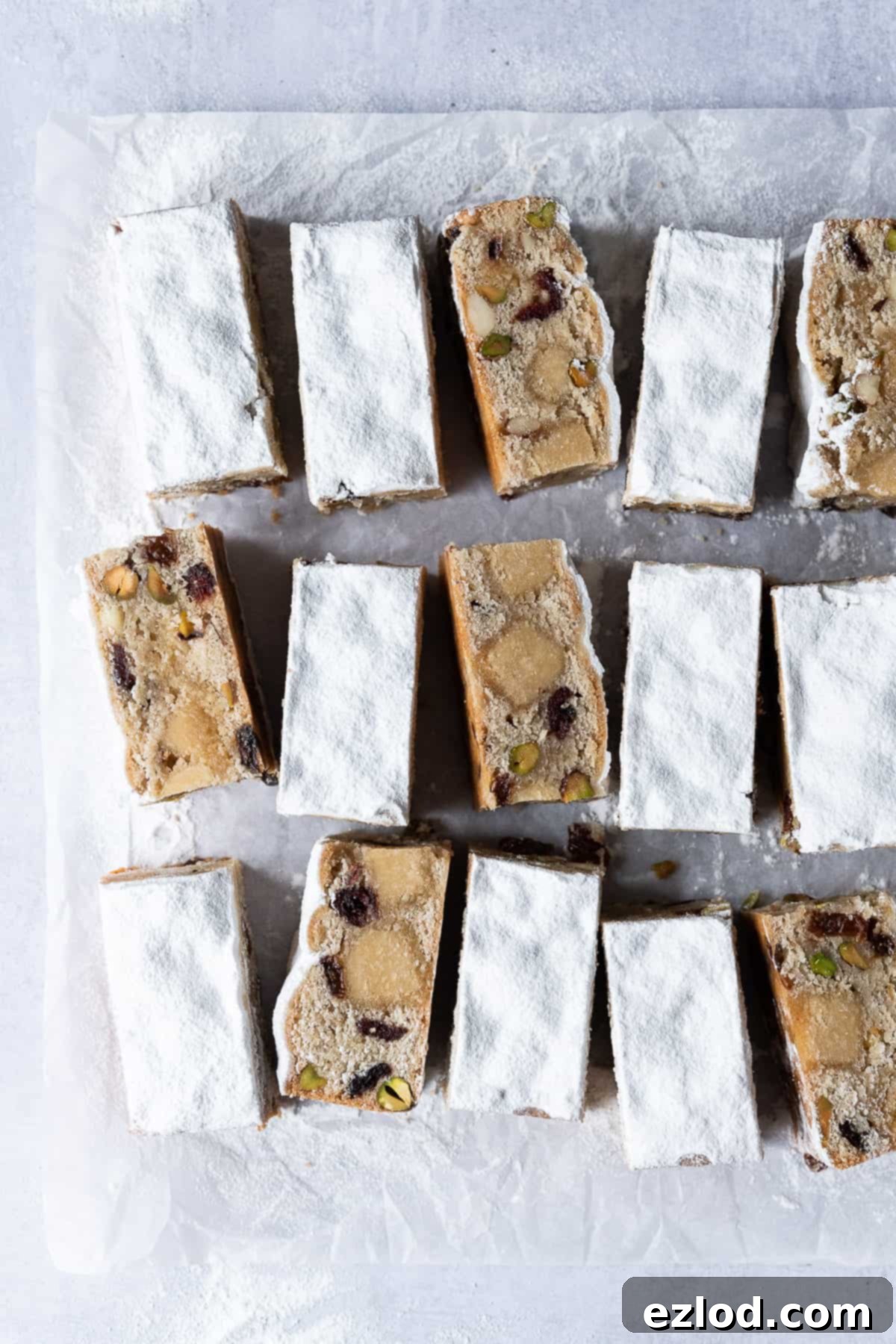 Delicious Vegan Stollen Bars: Your Go-To No-Yeast Holiday Treat. Vegan stollen bars on a sheet of white baking parchment on a grey background, ready for serving.