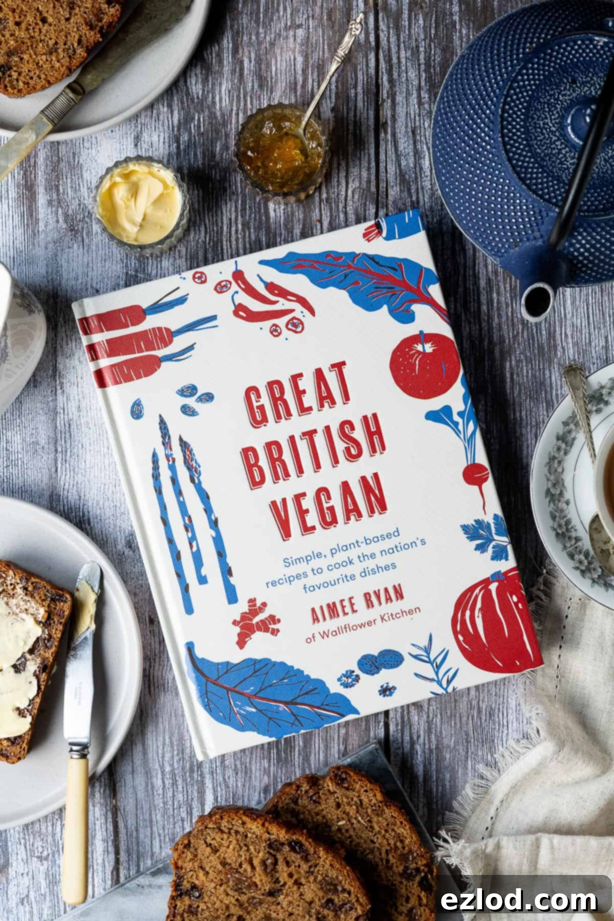Fragrant Vegan Earl Grey Tea Loaf 2 Great British Vegan cookbook open on a wooden table, surrounded by breakfast crockery including cups, saucers, and a small jug, inviting a cozy read.
