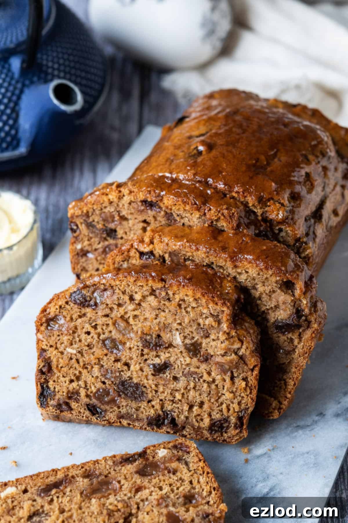 A close-up of delicious Vegan Earl Grey Tea Loaf slices. An easy, fat-free, fruity, eggless, and dairy-free cake. #veganbaking #vegancake #eggless #loafcake Sliced vegan tea loaf, showing off its rich fruit content and moist texture on a marble board.
