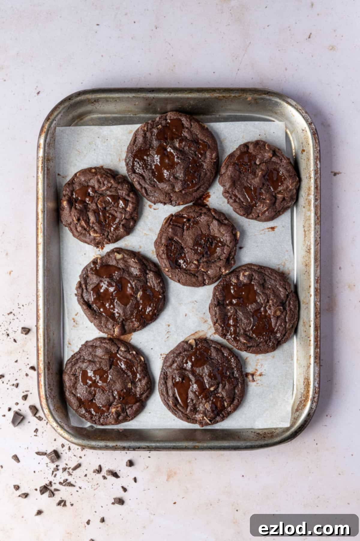Vegan double chocolate almond cookies – these rich, intensely chocolatey cookies are easy to make and taste amazing! They are crisp around the edges, gooey in the middle and are filled with chocolate chunks and almonds for an indulgent treat. Vegan double chocolate almond cookies on a metal baking tray.