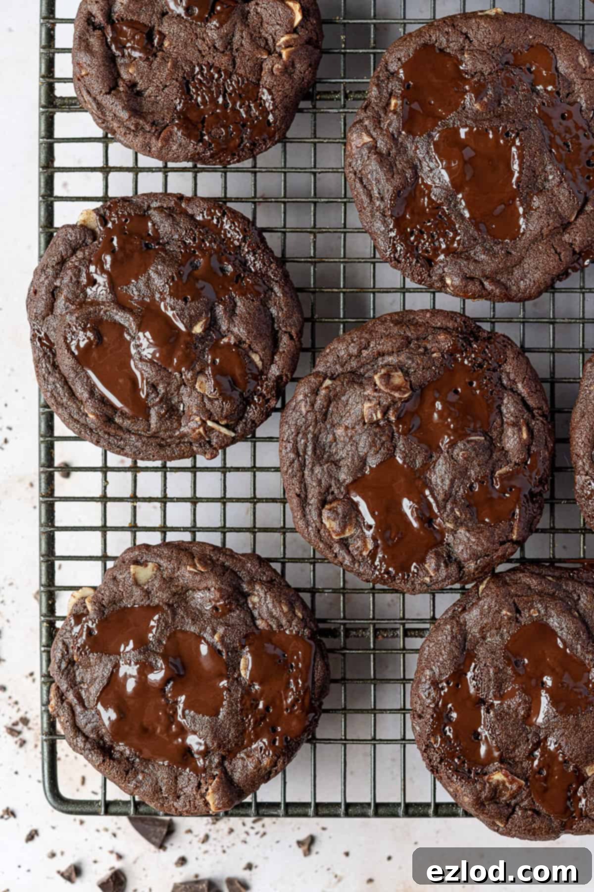 Vegan double chocolate almond cookies – these rich, intensely chocolatey cookies are easy to make and taste amazing! They are crisp around the edges, gooey in the middle and are filled with chocolate chunks and almonds for an indulgent treat. Vegan double chocolate almond cookies on a wire cooling rack.
