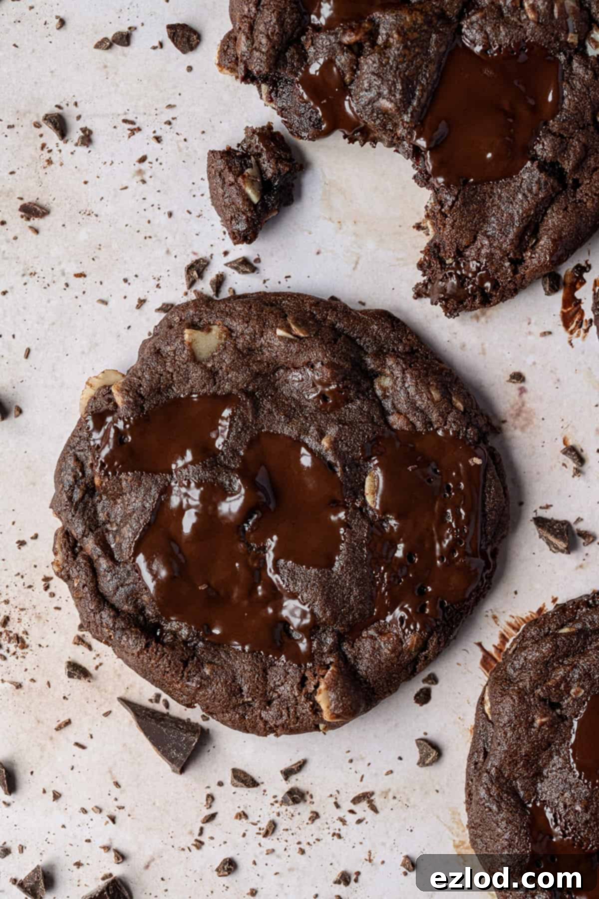 Vegan double chocolate almond cookies – these rich, intensely chocolatey cookies are easy to make and taste amazing! They are crisp around the edges, gooey in the middle and are filled with chocolate chunks and almonds for an indulgent treat. Close up of a double chocolate chip cookie.