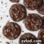 Vegan Double Chocolate Almond Dream 5 Vegan double chocolate almond cookies on a marble surface with a scattering of chopped chocolate.