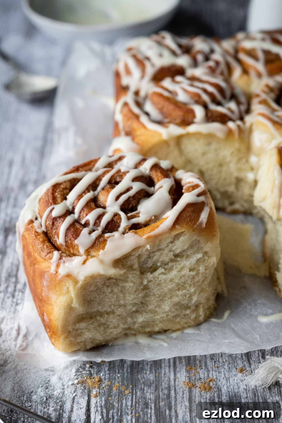 Vegan cinnamon rolls - these delicious cinnamon rolls are made using the tangzhong method which makes them incredibly soft, fluffy, squishy and moreish. Eggless and dairy-free. #veganbread #veganbaking #eggless #dairyfree A single vegan cinnamon roll on a wooden table, showcasing its soft, pillowy texture.