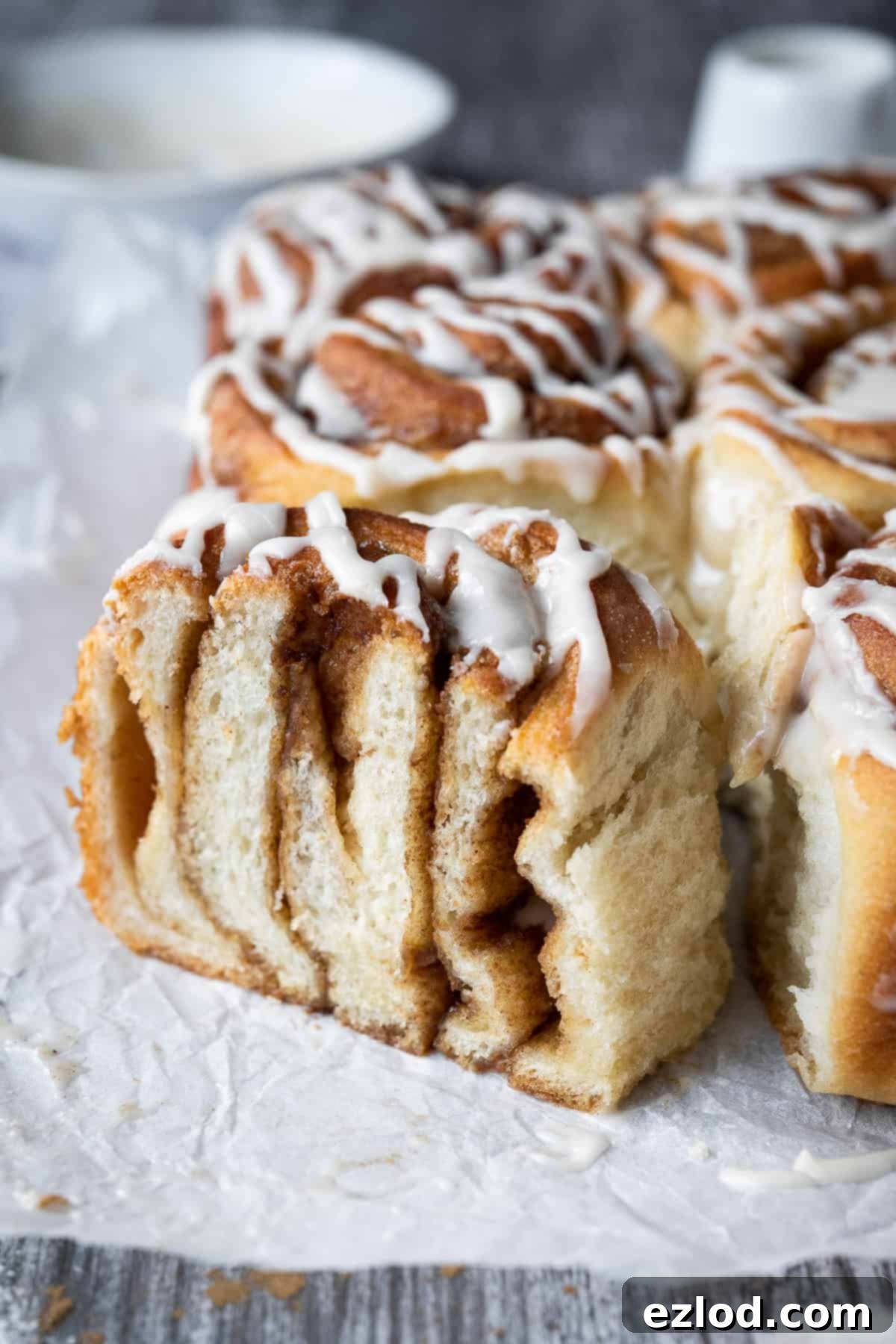 Vegan cinnamon rolls - these delicious cinnamon rolls are made using the tangzhong method which makes them incredibly soft, fluffy, squishy and moreish. Eggless and dairy-free. #veganbread #veganbaking #eggless #dairyfree Close up of a vegan cinnamon roll which has been sliced in half, revealing its beautiful layers of cinnamon sugar.