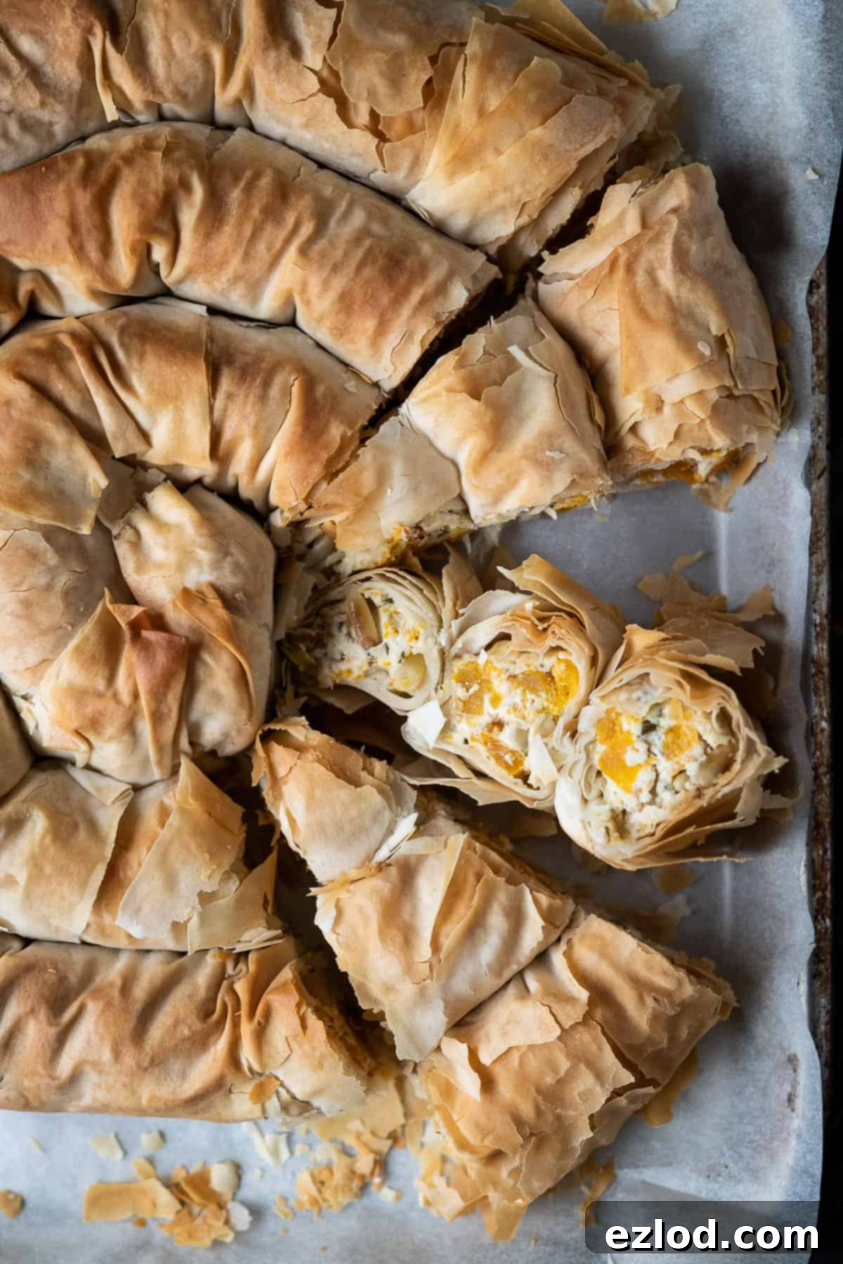 Vegan butternut squash and feta phyllo pie - this impressive vegan spiral pie is easier to make than it looks and tastes amazing! Roasted butternut squash is paired with tangy vegan almond feta cheese, herbs and a touch of chilli, all wrapped up in crisp filo pastry. #veganpie #veganbaking #veganmeal Close up of the sliced pie, one slice on it's side.