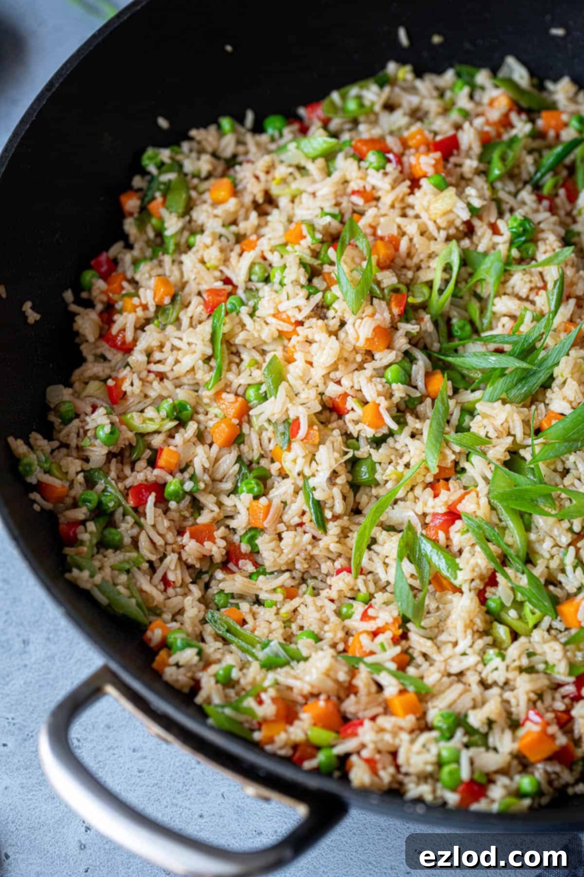 Freshly cooked vegan vegetable fried rice in a hot wok. Close up of vegetable fried rice sizzling in a wok, with a bright, fresh appearance.