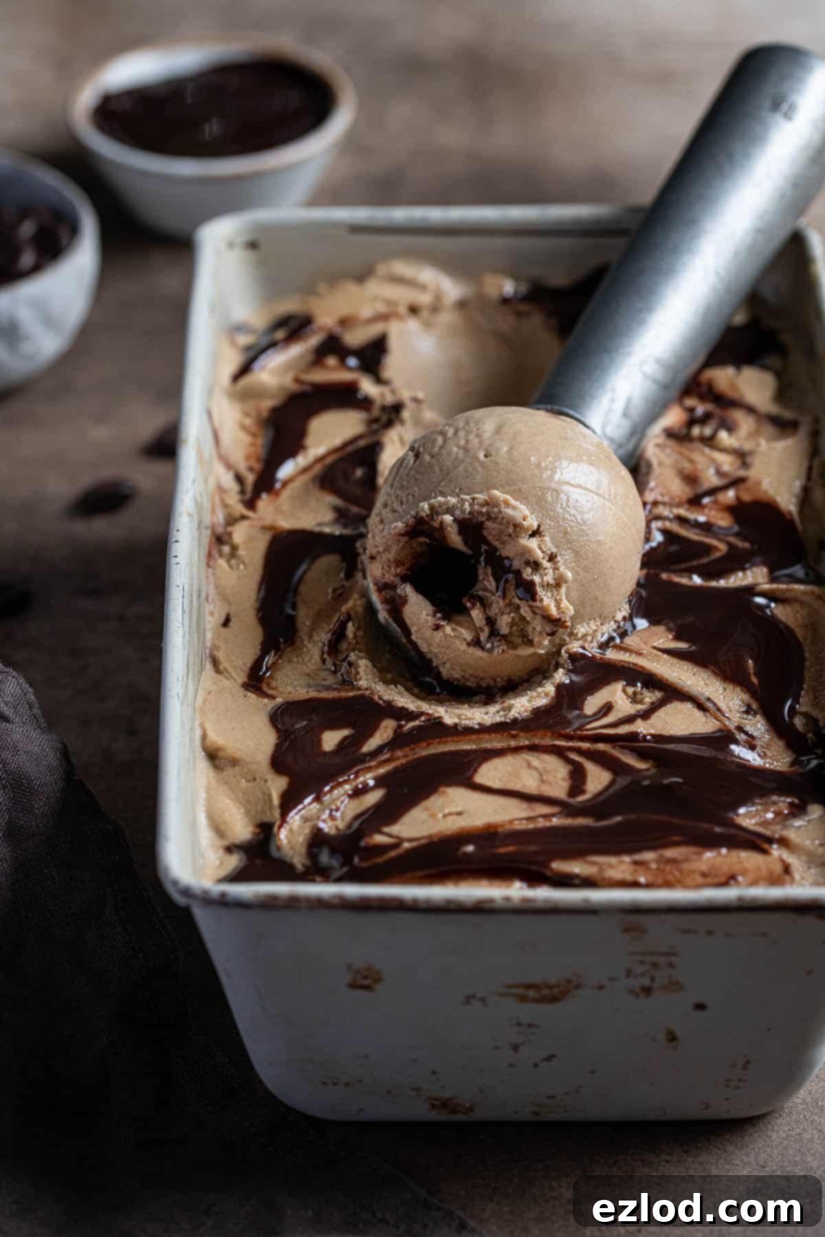 Experience the ultimate in vegan coffee ice cream: incredibly smooth, creamy, with a delightful coffee flavor and chocolate fudge swirl. Easy to make and completely coconut-free, thanks to the secret ingredient: oats! Vegan coffee ice cream in a metal tin with an ice cream scoop.