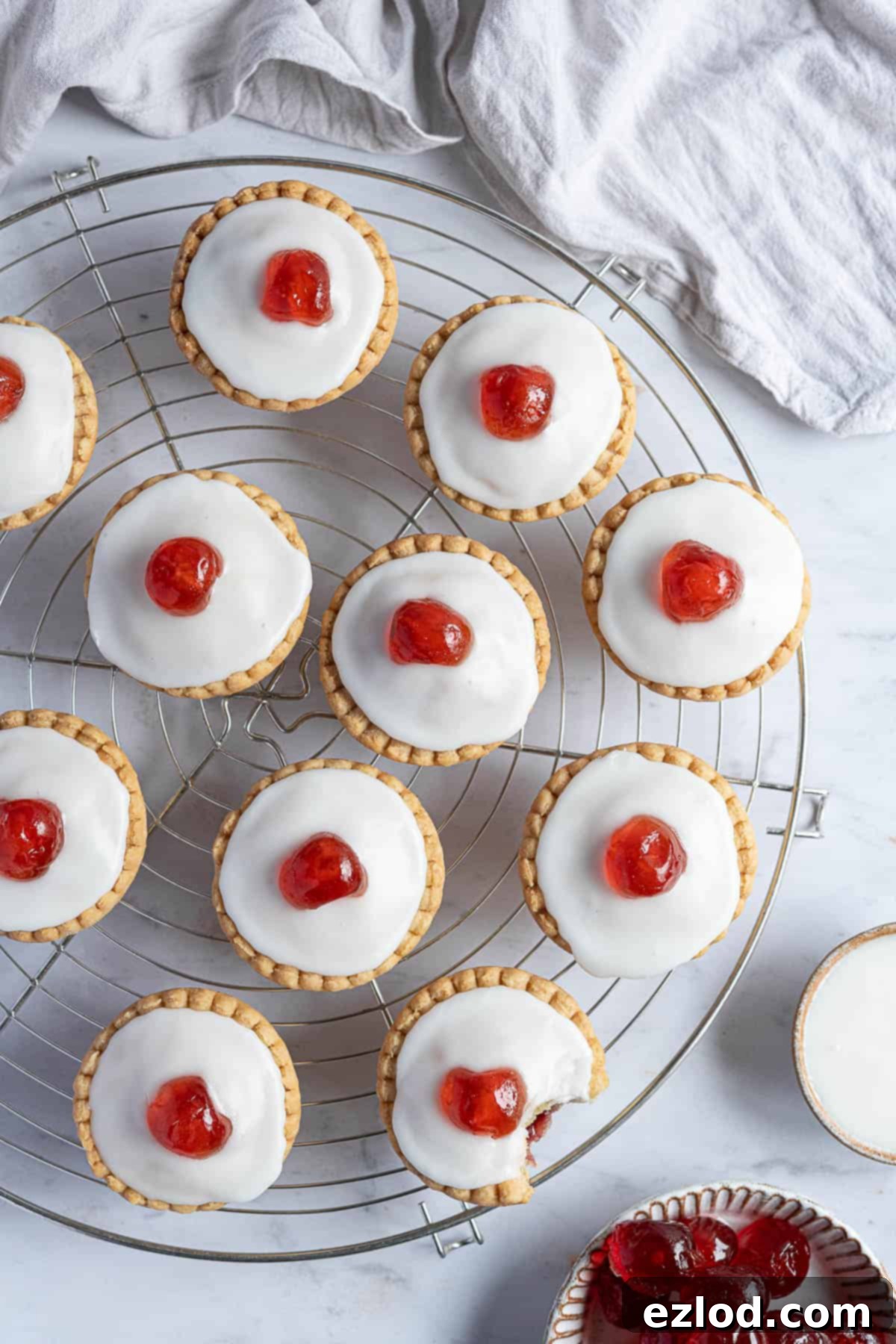 Irresistible Vegan Cherry Bakewells 11 Vegan cherry Bakewells on a round wire cooling rack.