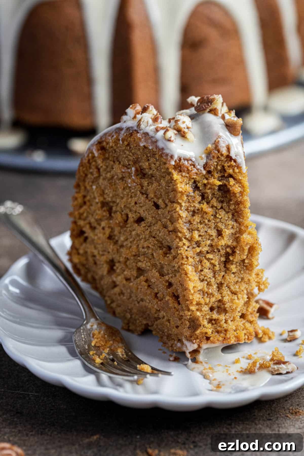 Cozy Vegan Pumpkin Bundt Delight 7 A close-up photograph of a sliced vegan pumpkin bundt cake with a forkful gently removed, showcasing its light, airy texture and inviting interior.