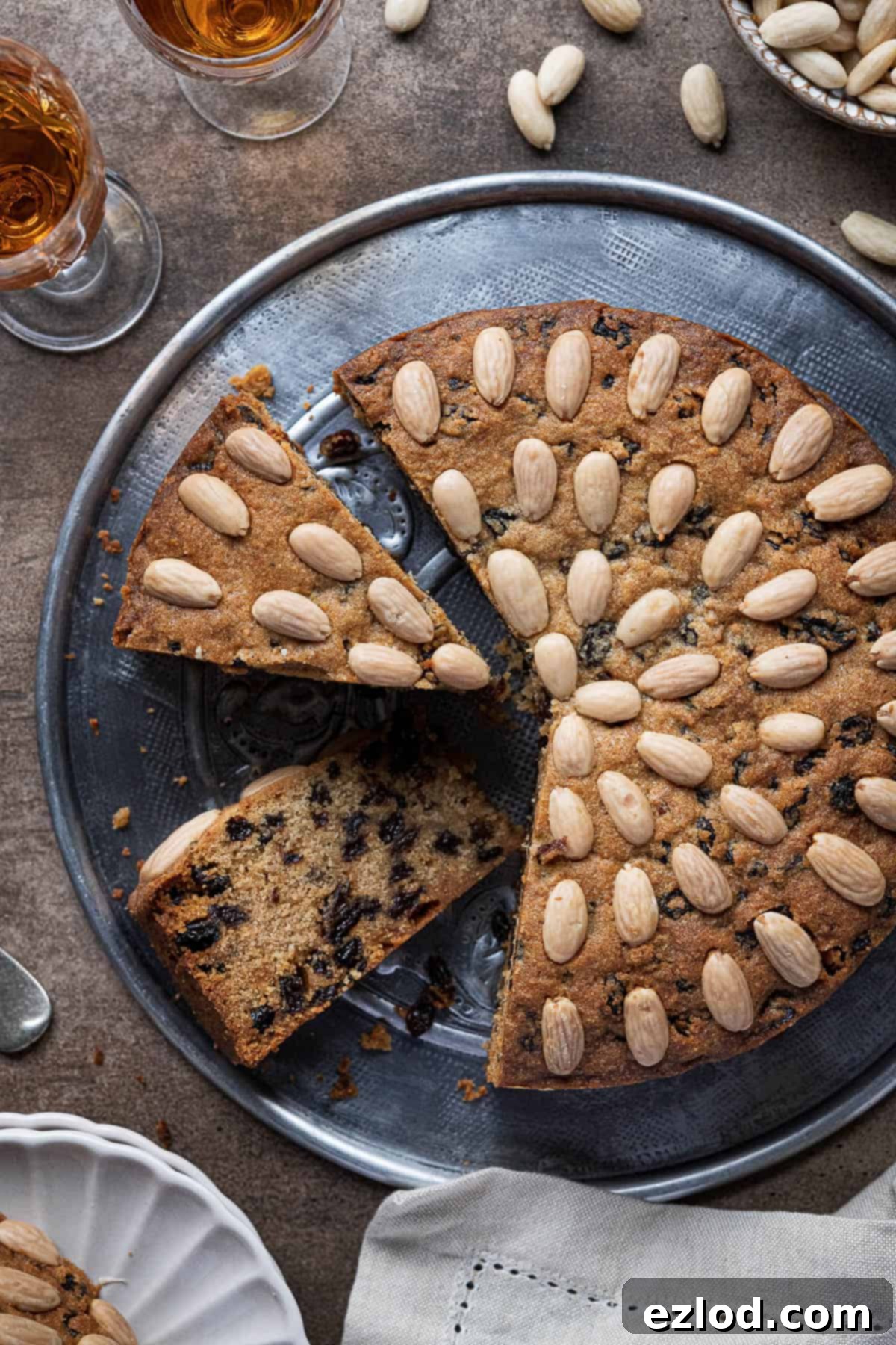 Plant-Based Dundee Cake 11 Vegan Dundee cake on a metal plate with two slices cut out.