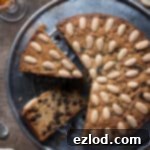 Plant-Based Dundee Cake 12 Vegan Dundee cake on a metal plate with two slices cut out.