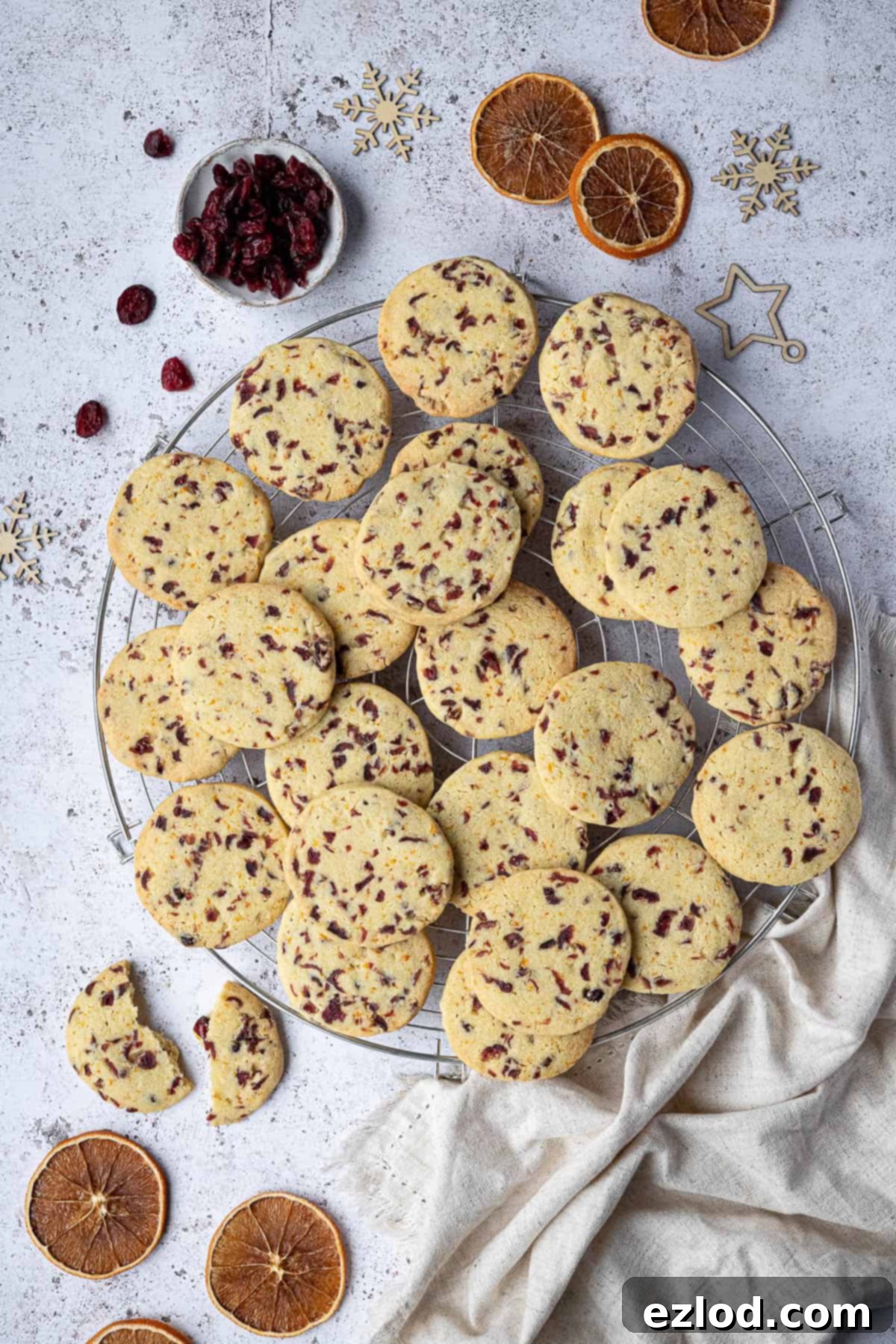 Vegan Zesty Cranberry Orange Shortbread 13 Beautifully arranged vegan shortbread cookies on a round wire cooling rack, festive with dried orange slices, cranberries, and holiday decor.