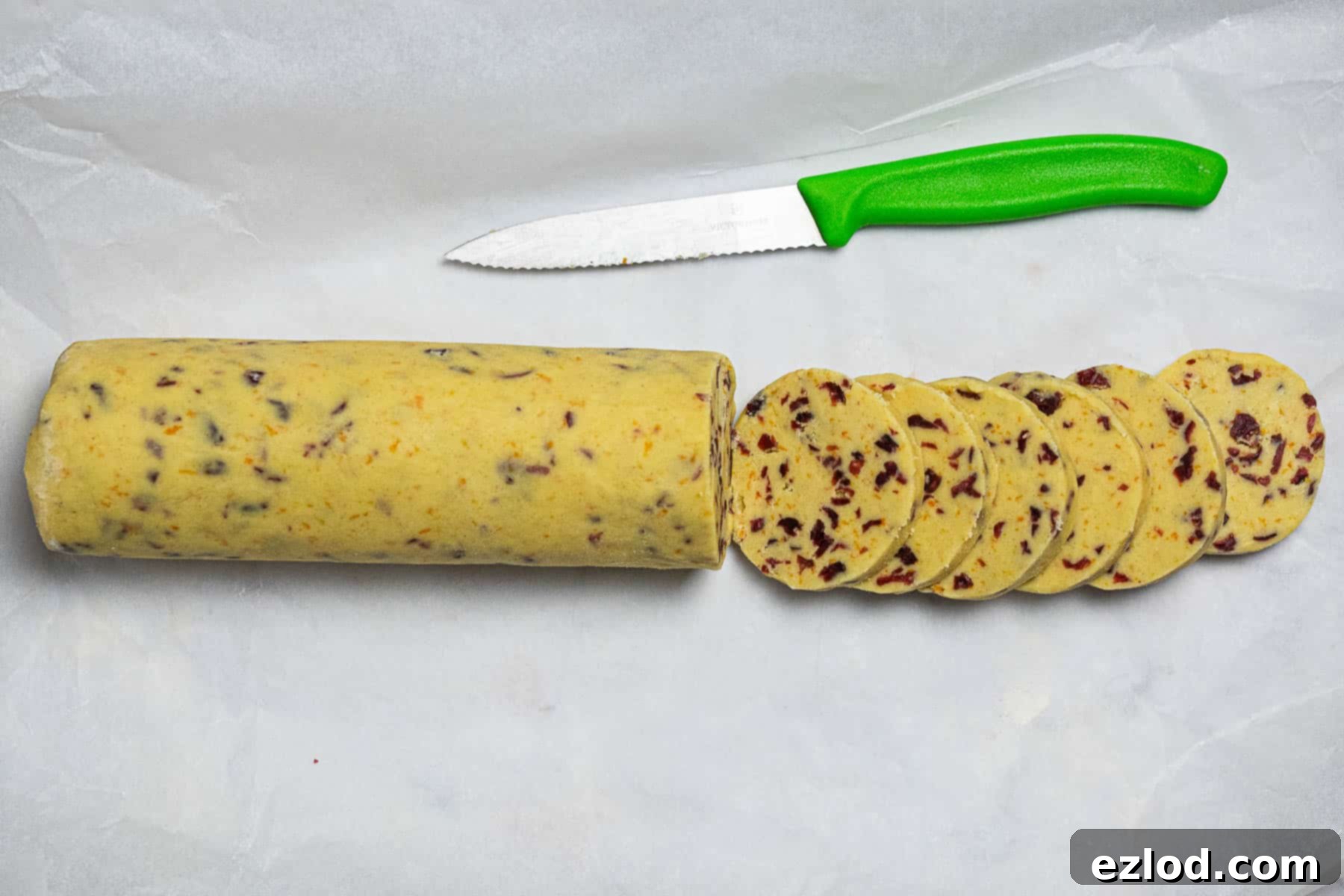 Vegan Zesty Cranberry Orange Shortbread 9 Step 6: Expertly slicing the chilled vegan cranberry orange shortbread dough log into even rounds using a sharp knife.