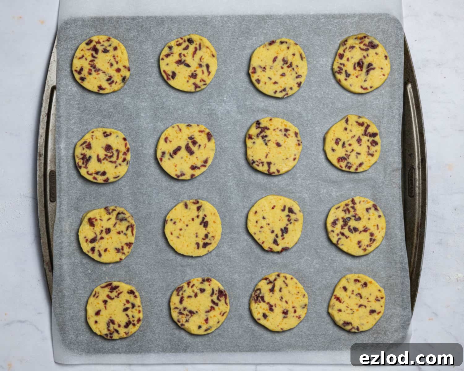 Vegan Zesty Cranberry Orange Shortbread 10 Step 7: Arranging the raw vegan shortbread cookie slices on a parchment-lined baking tray before baking.