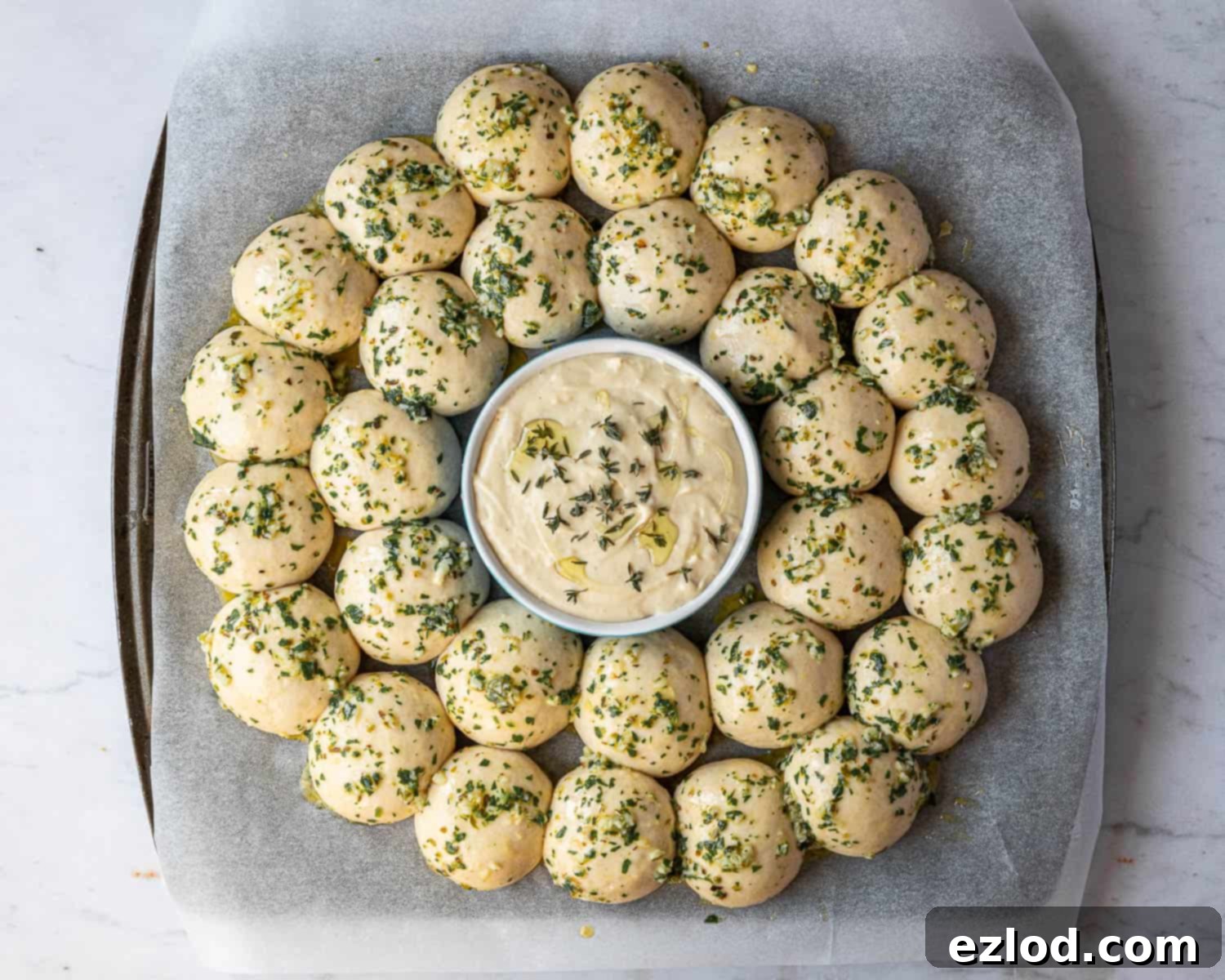 Pillowy Vegan Garlic Dough Balls 11 The arranged dough balls on a baking sheet, with the ramekin of cashew cheese dip in the center, brushed with garlic butter and ready for the oven.