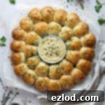 Pillowy Vegan Garlic Dough Balls 15 Vegan garlic dough ball wreath on a sheet of baking parchment surrounded by bowls of herbs and garlic butter.