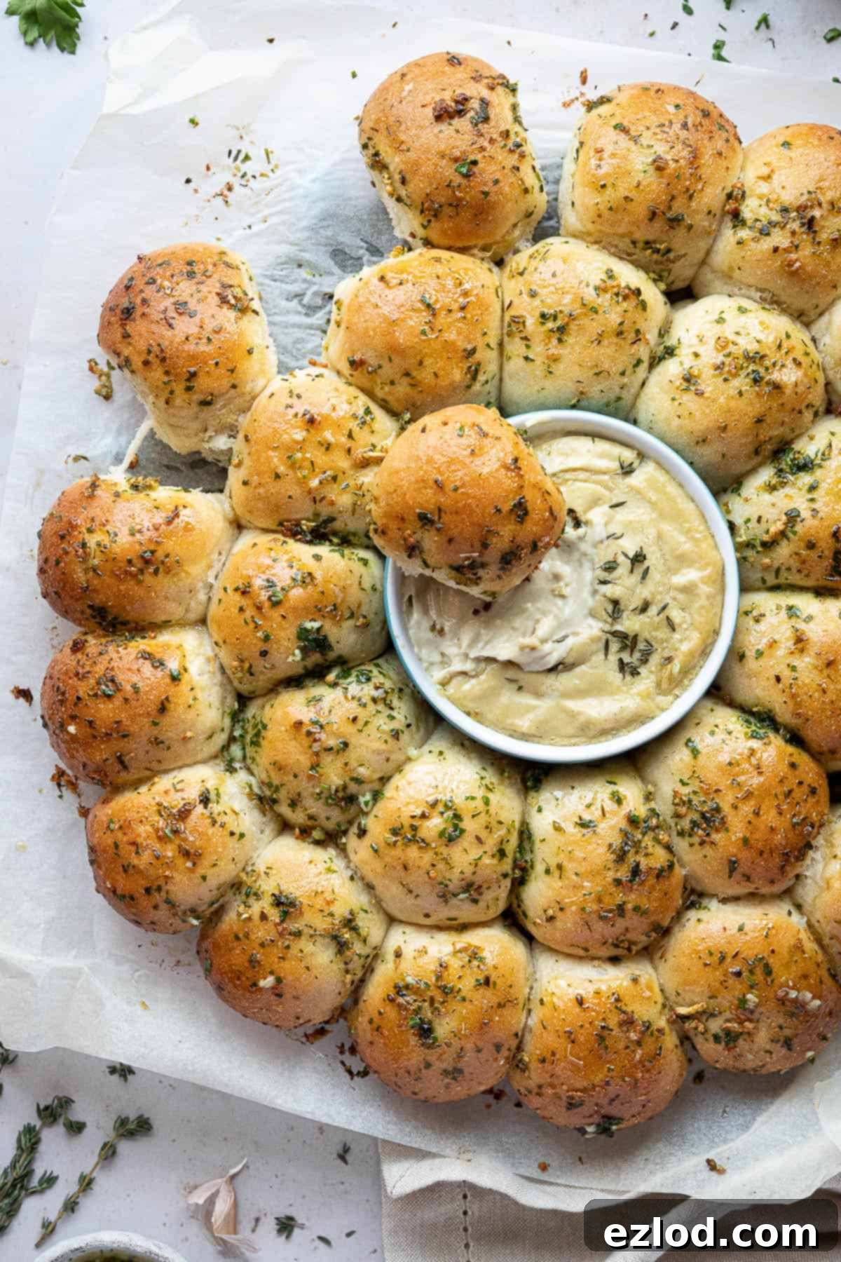 Pillowy Vegan Garlic Dough Balls 3 A close-up shot of a golden vegan garlic dough ball, freshly baked and glistening with garlic butter, being dipped into a small bowl of creamy, yellow cashew cheese dip. The textures are inviting and appetizing.