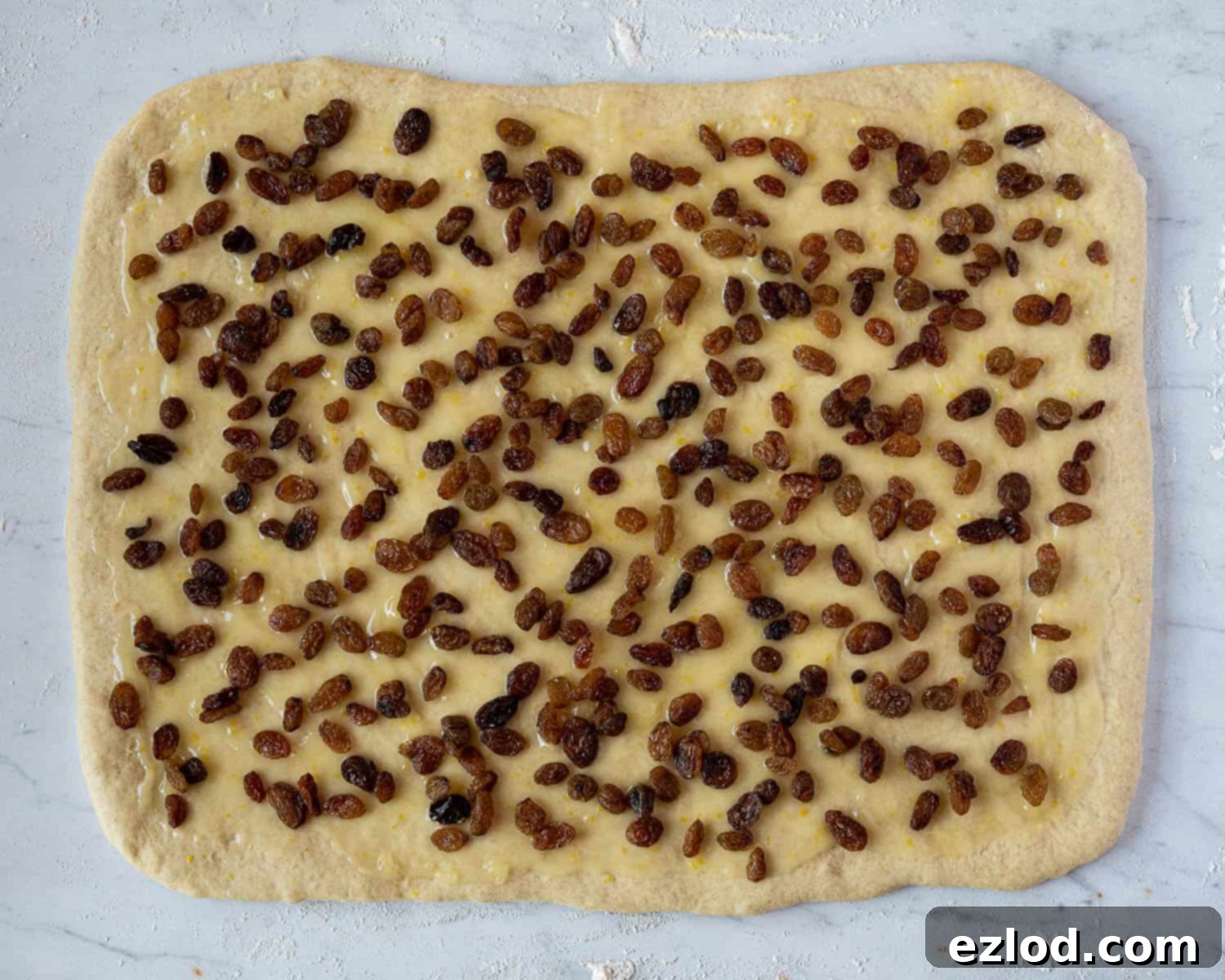 Plant-Based Belgian Delights 5 Step 3, the rolled out dough topped with lemon curd and sultanas.
