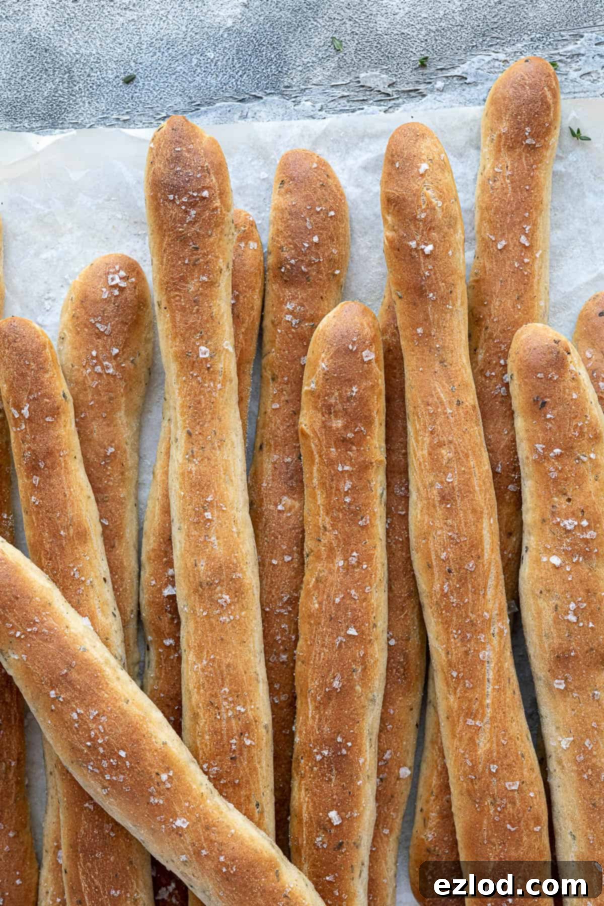 Aromatic Plant Sticks 10 Close-up of freshly baked herby vegan breadsticks arranged on baking parchment, highlighting their golden crust.