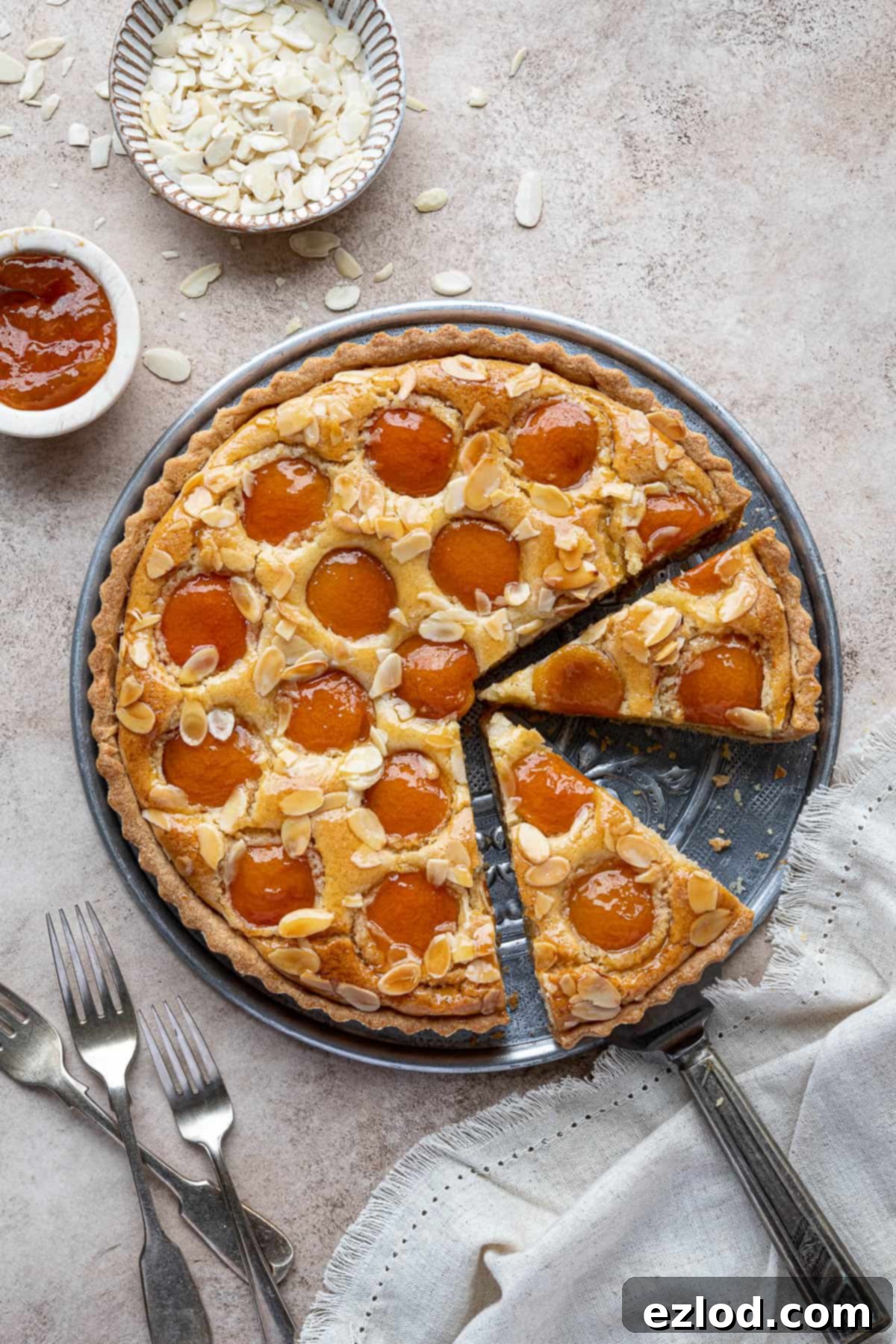 Plant-Based Apricot Frangipane Tart 10 A perfectly sliced vegan apricot frangipane tart, showcasing its interior on a metal plate, ready to be served.