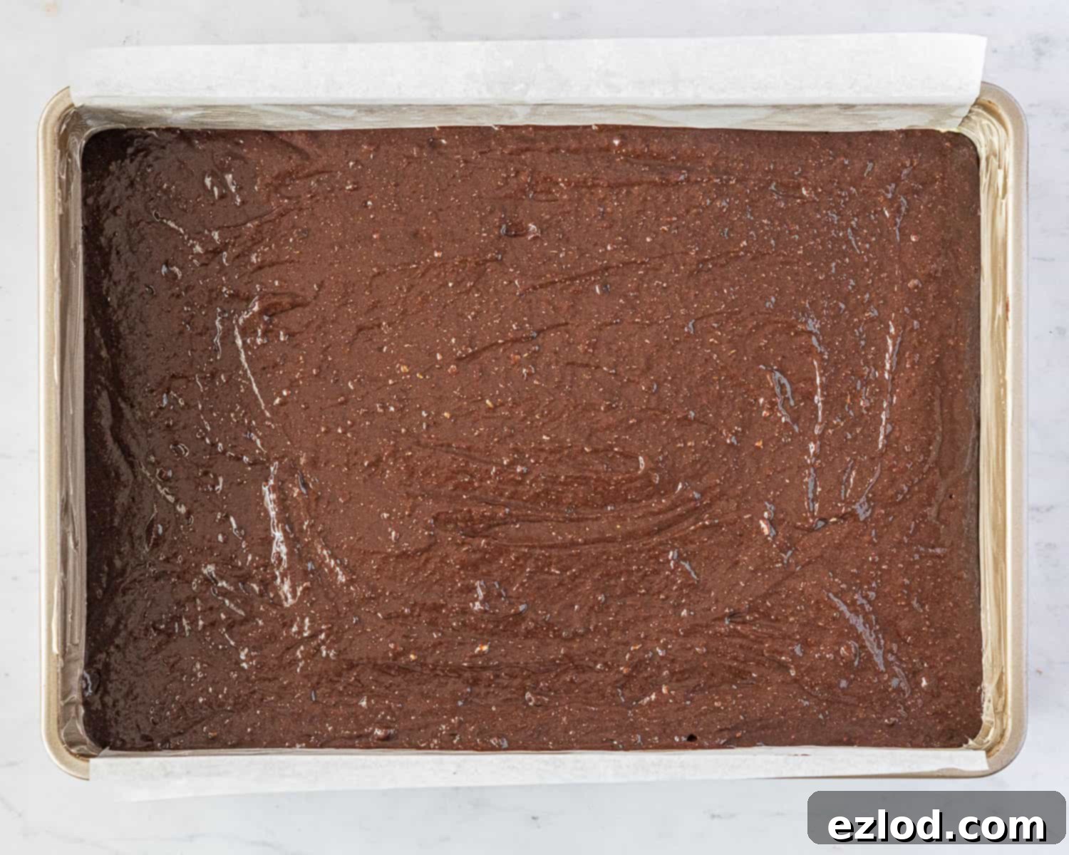 Decadent Vegan Chocolate Hazelnut Cake 8 The smooth vegan chocolate hazelnut cake batter has been evenly poured into a greased and lined rectangular cake tin, ready for baking.