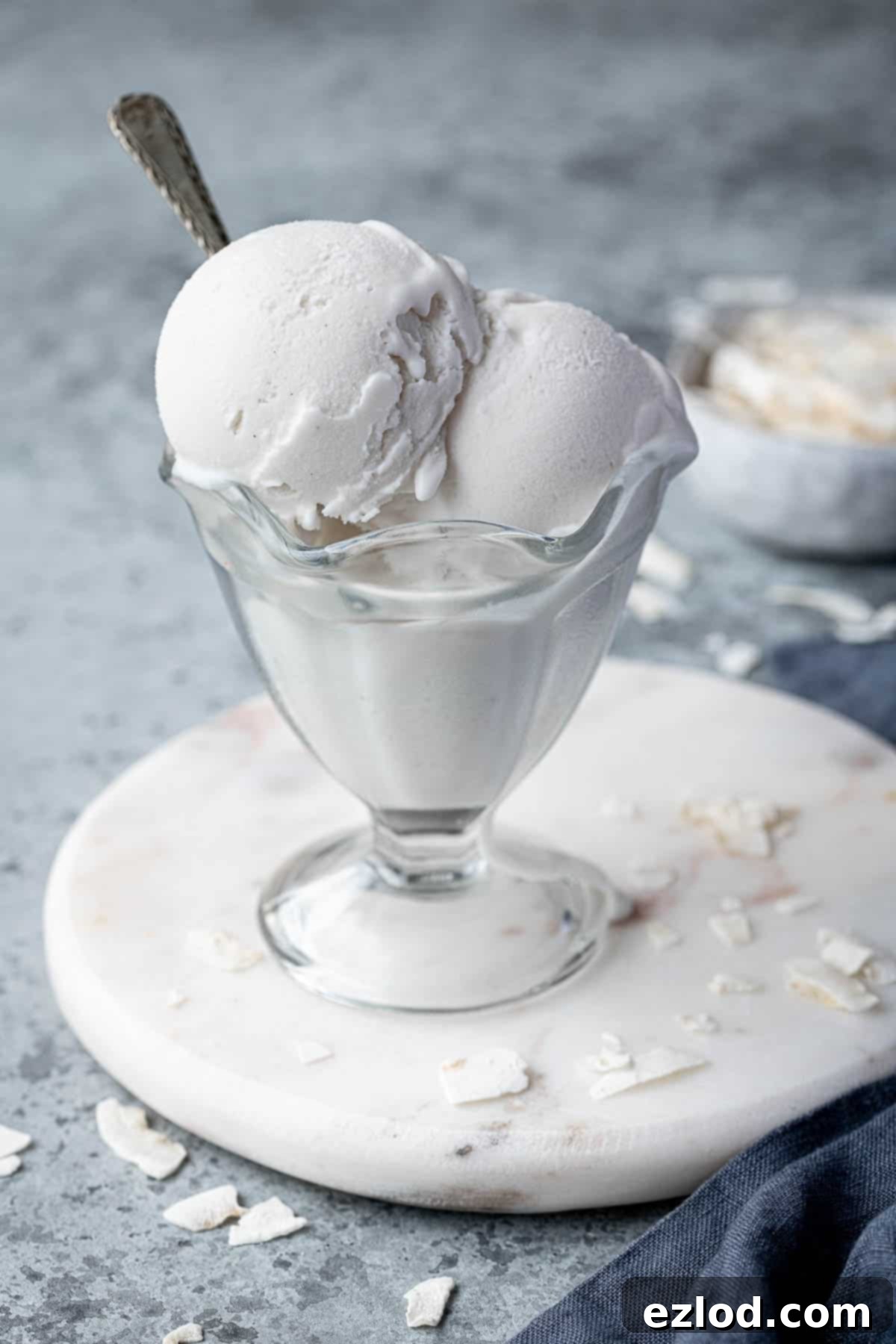 Effortless Vegan Coconut Ice Cream 5 A beautiful sundae glass filled with scoops of easy coconut ice cream, garnished attractively, ready to be served.