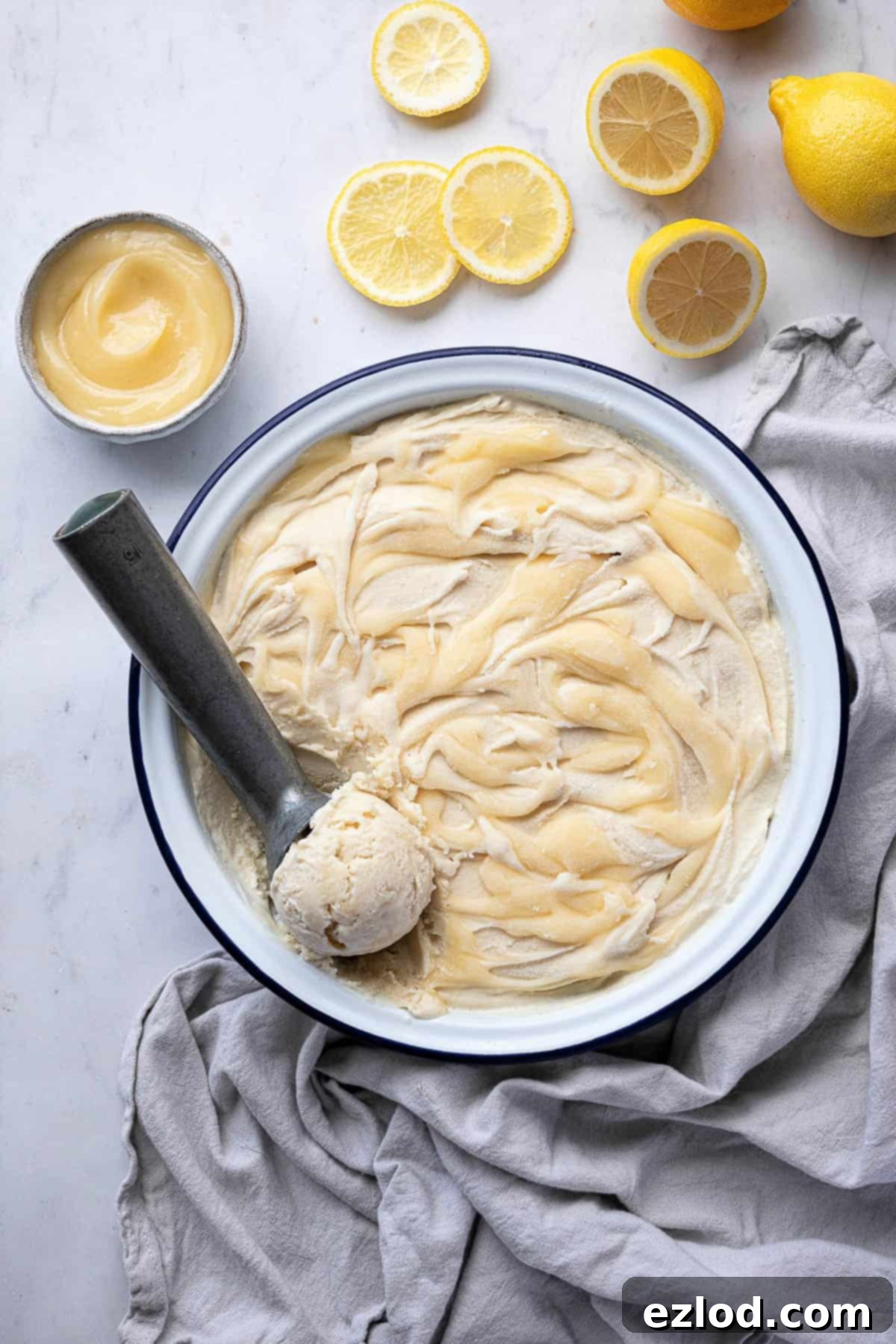 Refreshing Vegan Lemon Delight 4 A beautifully composed shot featuring a bowl of vegan lemon ice cream, an ice cream scoop, fresh lemon slices, and a separate bowl of homemade lemon curd, ready for serving.
