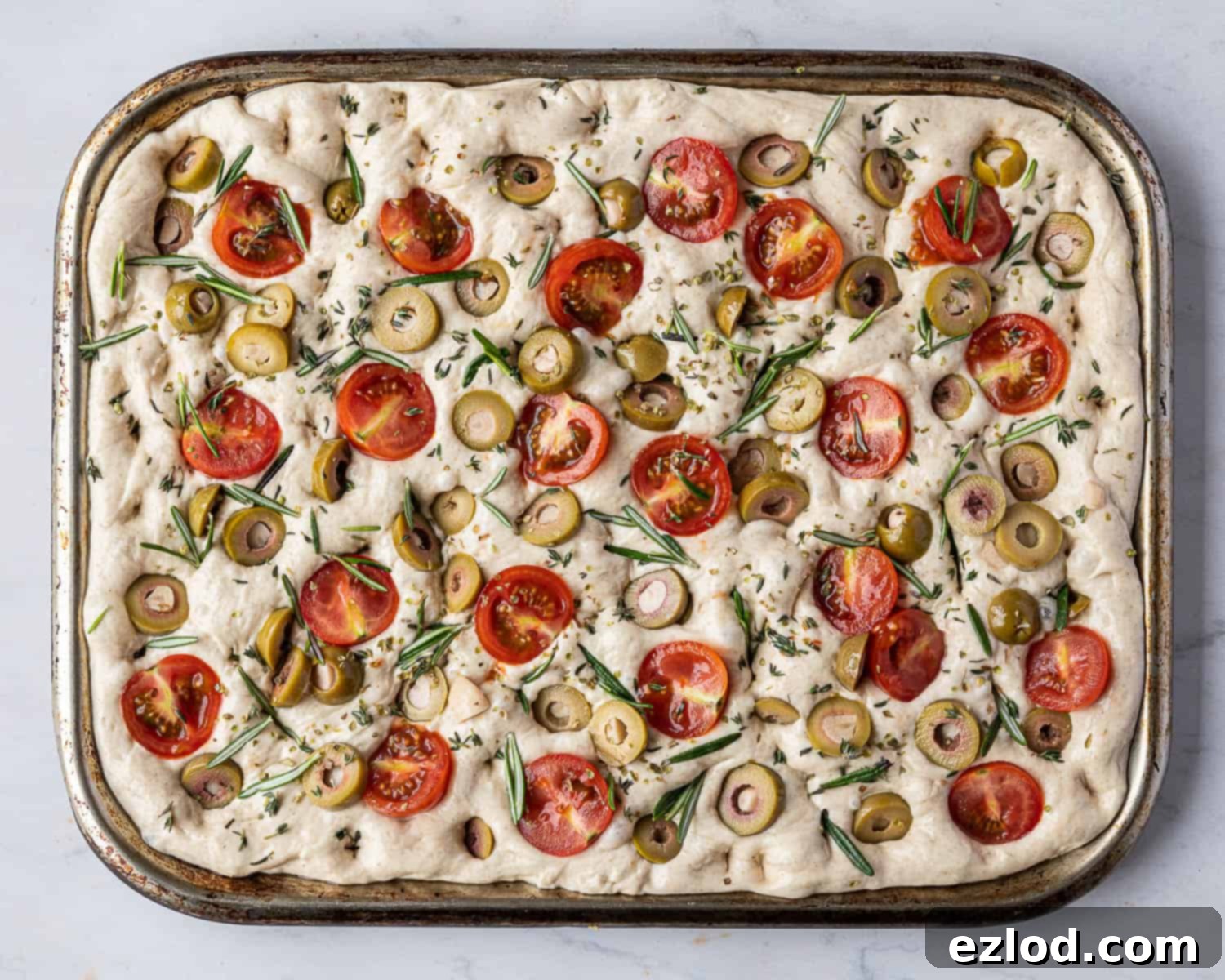 Baking Bliss and BBC Maestro Insights 11 Step 7, the focaccia dough fully topped with olives, tomatoes, and herbs, ready for the final rise.