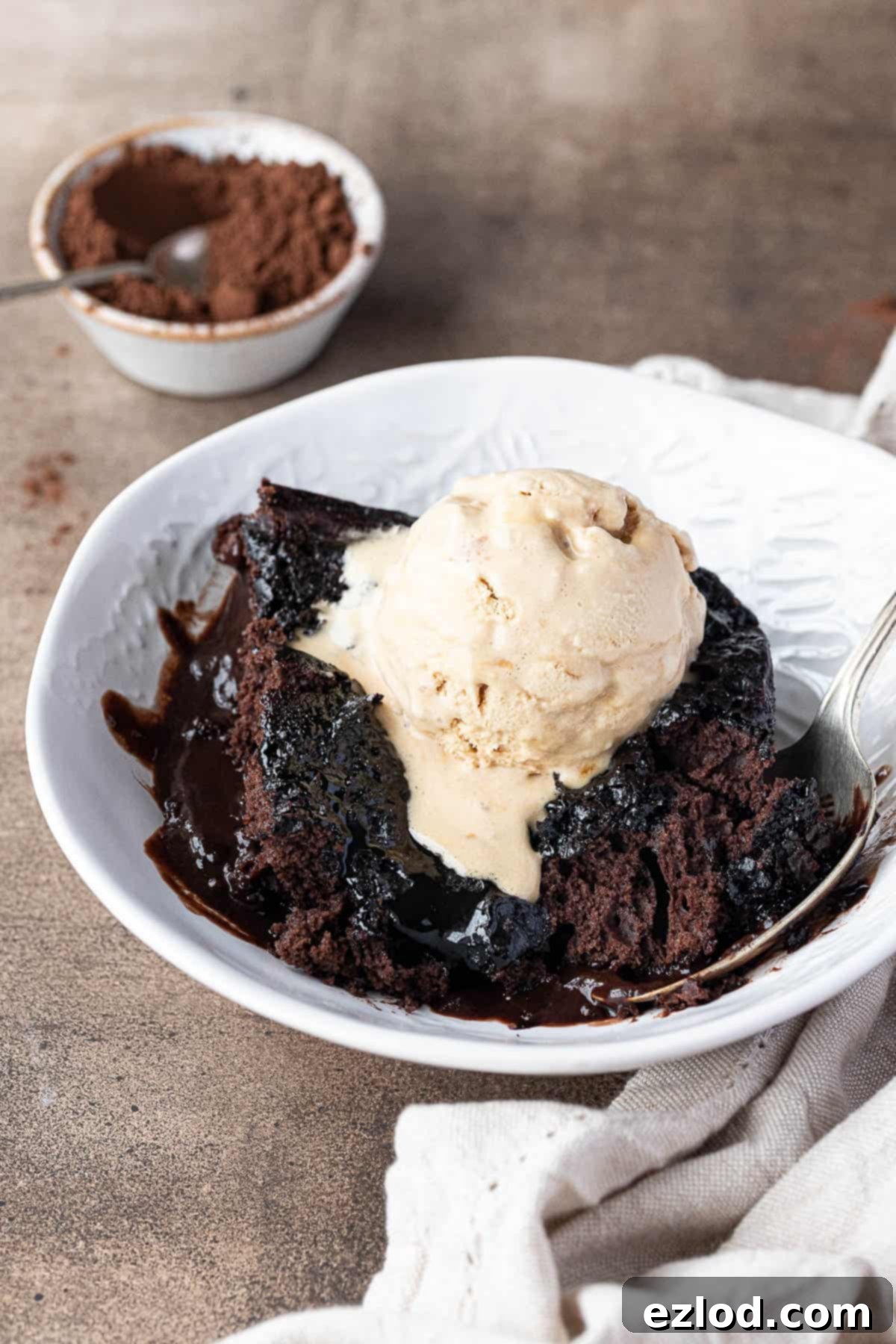 Decadent Vegan Chocolate Lava Pudding 3 A slice of self-saucing chocolate pudding in a bowl with a scoop of ice cream.