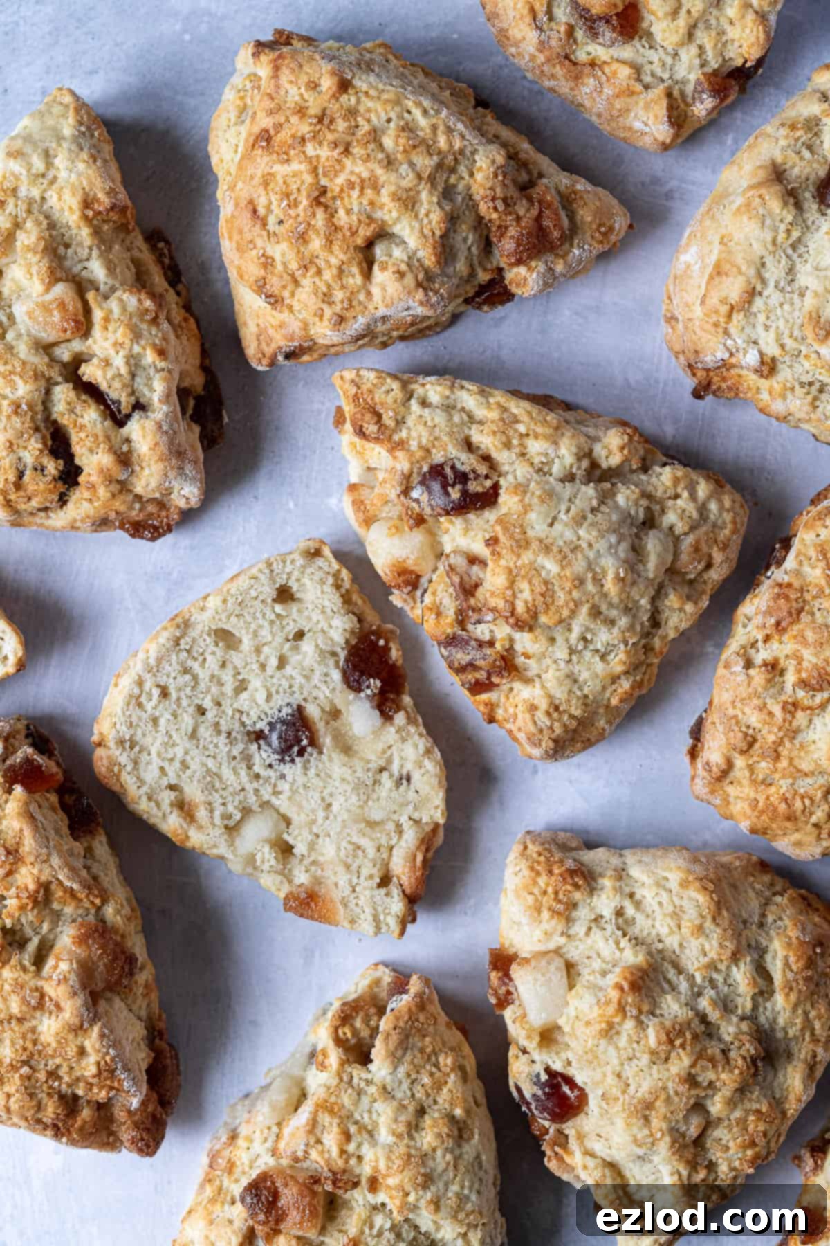 Homemade Vegan Marzipan Cherry Scones - Fluffy, Fruity, and Absolutely Delicious! Perfectly baked vegan marzipan cherry scones arranged on a rustic grey surface, with one scone beautifully sliced in half to reveal its tender, fruit-speckled interior.
