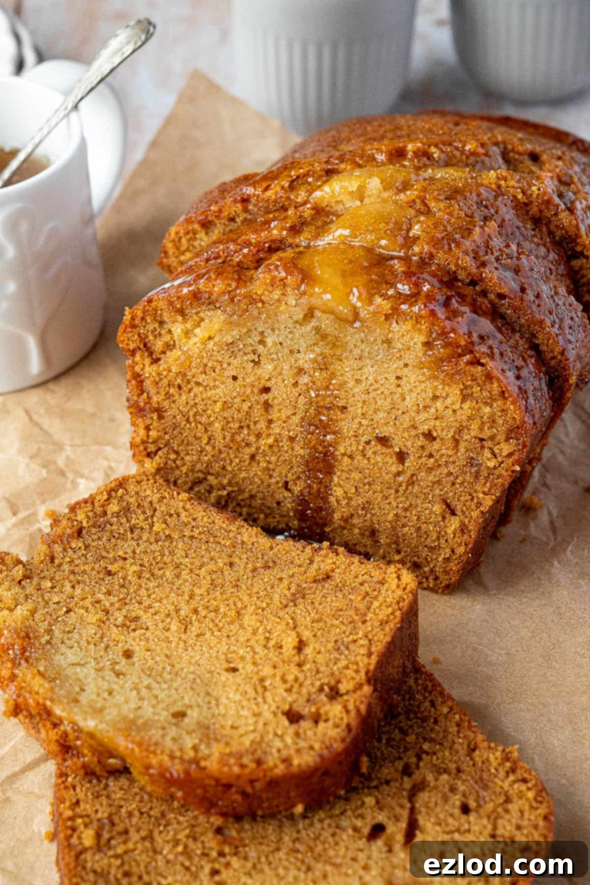 Vegan Liquid Gold Cake 4 A beautifully sliced vegan golden syrup cake displayed next to a charming jug of golden syrup, highlighting the cake's inviting appearance and the key ingredient.