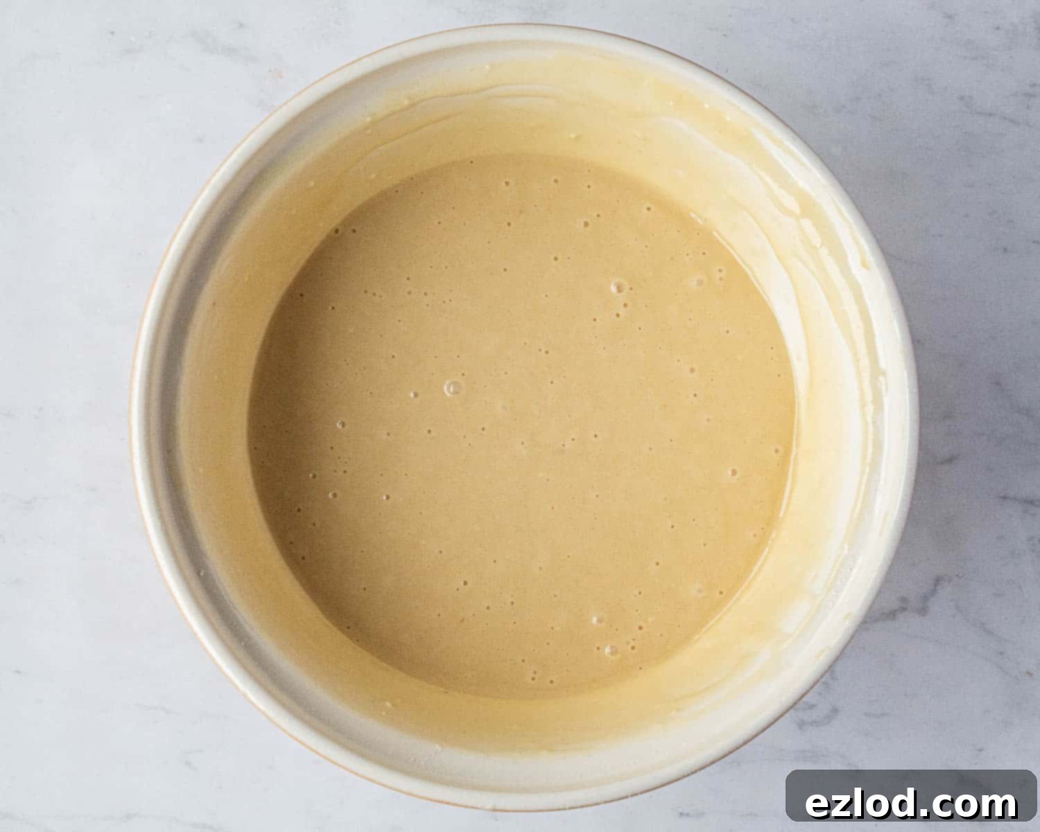 Vegan Liquid Gold Cake 6 Step-by-step image showing the smoothly mixed batter for the vegan golden syrup cake in a large bowl, ready for baking.