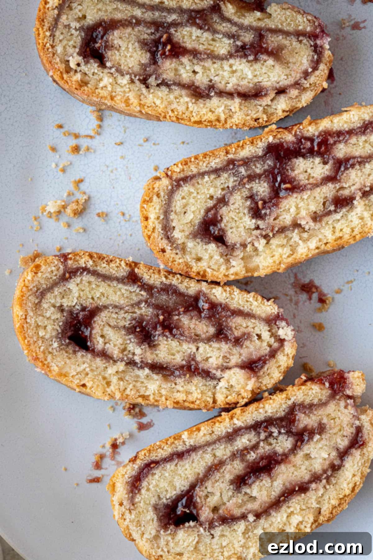 Luscious Vegan Jam Roly-Poly 2 Close-up of golden brown slices of vegan jam roly-poly, showing the swirl of red jam within the pastry.